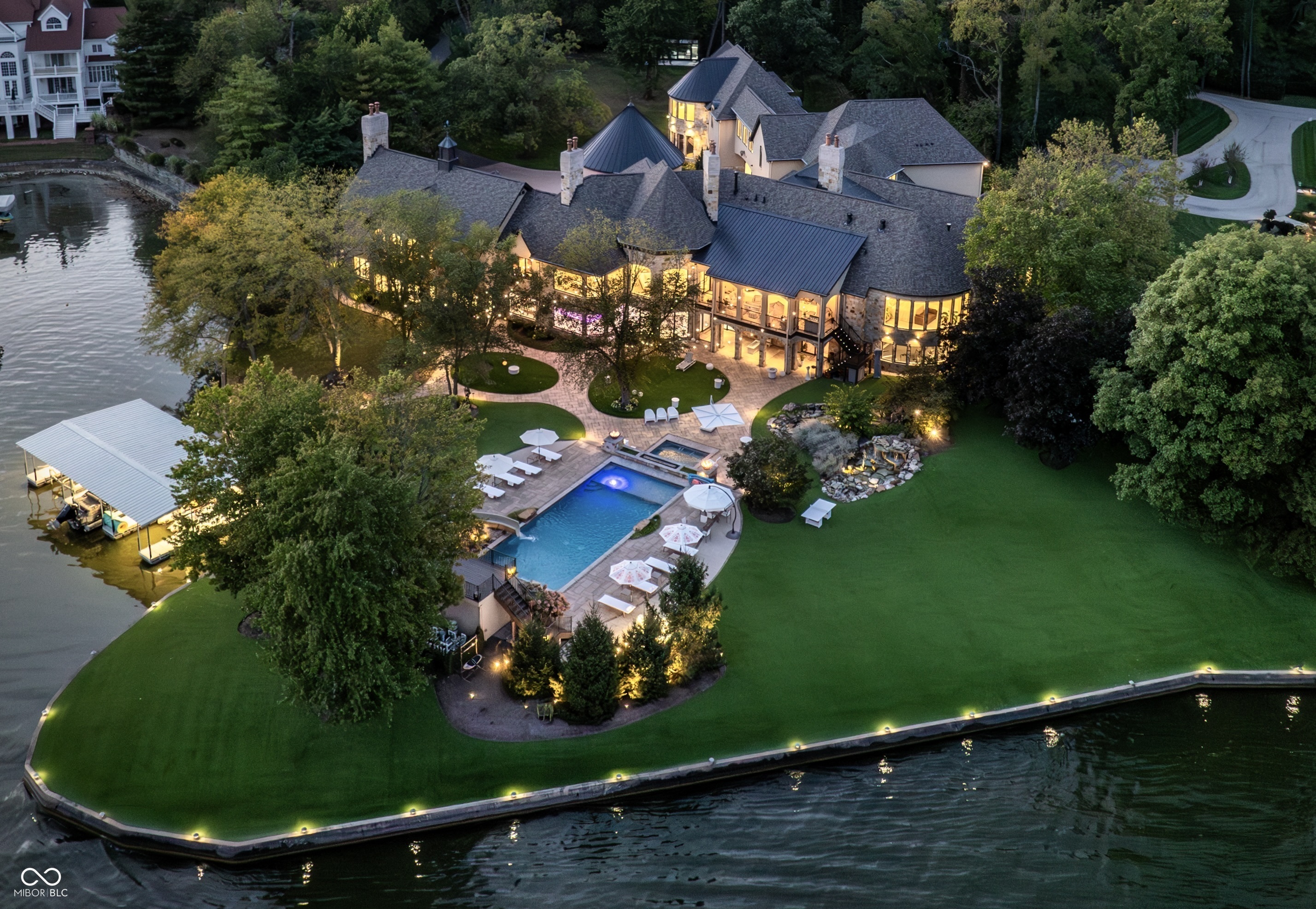 Set on 5.23 PRIVATE ACRES with 570' of pristine Geist Reservoir shoreline, this 21,000 sq ft gated waterfront estate redefines Midwestern luxury. A gas-lit, tree-lined drive leads to The Andretti Estate, featuring 9 bedrooms, 12 bathrooms, 7 fireplaces & surrounded by manicured lawns, wooded trails & sweeping open-water views. Inside, craftsmanship & technology merge seamlessly with integrated automation, a three-level elevator & advanced security enhancing everyday life. The main level unfolds with breathtaking vistas from every gathering space, including a fireside study that leads to the estate lounge with bar, billiards area & sitting rooms. The culinary space showcases dual kitchens: a discreet caterer's kitchen is steps away from the primary, featuring commercial-grade appliances, a 14' island, and seamless flow to a 38' heated veranda with grilling area, retractable screens, and sweeping lake views. An elegant anteroom leads to the private owner's wing with a relaxing reading room & coffee nook. A double-sided fireplace is shared with the primary bedroom, its curved walls framing lake views through a full wall of windows. A spa bath rests beneath a glass-tiled barrel ceiling, while 650 sq ft of closet space completes the suite. The upper level offers two wings, one with a loft & 2 en suite bedrooms, the other a guest wing with kitchen, living room, 2 en suite bedrooms, laundry & garage access. The resort-style walkout level presents a 15-seat bar, 700 bottle wine cellar, theater, arcade, billiards room, fitness studio, 4 bedrooms, 5 baths & 4 exterior exits. The outdoor space features a 50' gunite pool with slide, jacuzzi, waterfalls, fire features, multiple patios, a children's play cottage with HVAC & a 50' three-slip boat dock. A newer carriage house includes two 900 sq ft apartments, each with a kitchen, en suite bedroom, living room, laundry & 2-car garage. 5,500 sq ft of climate-controlled garage space with 12+ bays completes this unparalleled estate.