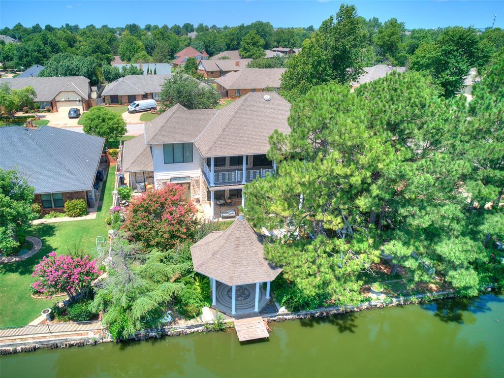 Rare lakefront opportunity on 1.09 acres in Lakeridge Run, offering breathtaking water views and over 5,000 square feet of living space thoughtfully designed to take full advantage of its setting. Expansive windows frame panoramic lake views and fill the home with natural light. A striking double-sided stone fireplace anchors the main living area and adjoining library, while crystal chandeliers add a warm, refined glow throughout the home. The main-level primary suite features a whirlpool tub and dual walk-in closets, with two additional bedrooms also on the main level. Upstairs, a custom iron staircase leads to a private suite and flexible living space ideal for guests or recreation. Outdoor living includes a balcony, covered patio, gazebo, fishing dock, and firepit with built-in seating overlooking the lake. The 1.09-acre property extends across the lake to include the opposite shoreline, enhancing privacy and the natural setting. Ideal for both peaceful lakeside living and effortless entertaining.