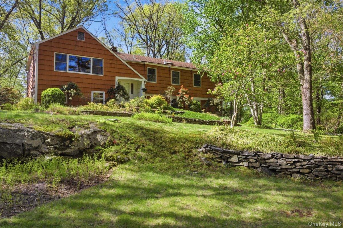 Discover tranquility in this stunning five-bedroom home at the end of a peaceful cul-de-sac. Nestled on a hillside plateau, the property boasts privacy and natural beauty, highlighted by lush ferns and a cascading stone stairway leading to an artfully designed waterfall and fish pond. Step into the light-filled foyer that opens to a spacious living room and a formal dining room, both perfect for entertaining. The eat-in kitchen provides a warm gathering space.  Conveniently located on the main floor is the primary suite, complete with an ensuite bath and ample closet space, along with three additional bedrooms—two currently utilized as an office and gym—and a full hall bath with double sinks shower/tub with jacuzzi.The lower level features a large bedroom, a cozy family room with a fireplace, a laundry room, and a newly renovated accessible bathroom. A sliding door from the family room leads to the backyard, enhancing your outdoor enjoyment. This home seamlessly blends comfort, style, and nature, making it an ideal retreat for those seeking a serene lifestyle. Property has security cameras