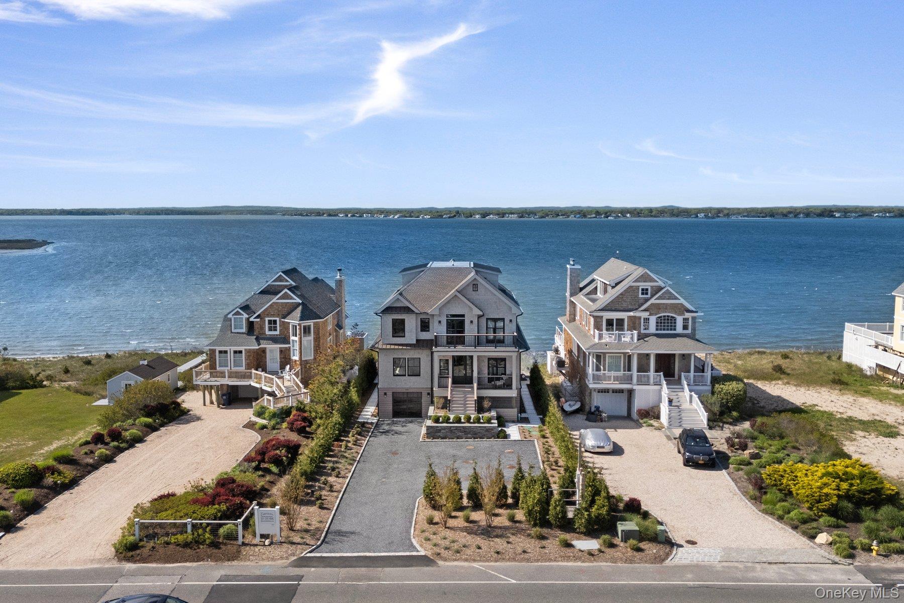 Welcome to 686 Dune Road, an exquisite bayfront retreat in Westhampton Dunes, where luxury and thoughtful design converge. Built by Elderco, this custom home promises an unparalleled living experience with no detail overlooked. The heart of the home is the state-of-the-art kitchen, a culinary haven featuring a Sub-Zero refrigerator, Wolf double wall oven and cooktop, and a serving station with a double wine fridge. The open layout flows seamlessly into the living and dining areas, offering expansive bay views. The primary suite is a true sanctuary, featuring two walk-in closets, a wet/coffee bar with an additional wine fridge, and an expansive balcony deck to enjoy stunning sunsets. Relax in the spa-like bathroom with radiant heated floors and a Neorest Toto toilet, or indulge in the incredible outdoor shower year-round. This home boasts five spacious bedrooms, each offering bay or ocean views, and six-and-a-half bathrooms. An elevator provides easy access across all levels, including the third floor, which features a full bathroom and is perfect for a TV area, gym, or game room. Laundry rooms are conveniently located on both the first and second floors. Enjoy the tranquility of the infinity gunite heated pool overlooking the bay, with privacy screening on the back deck. A one-car attached garage completes this exceptional property. Experience the ultimate in bayfront living at this stunning Dune Road home!