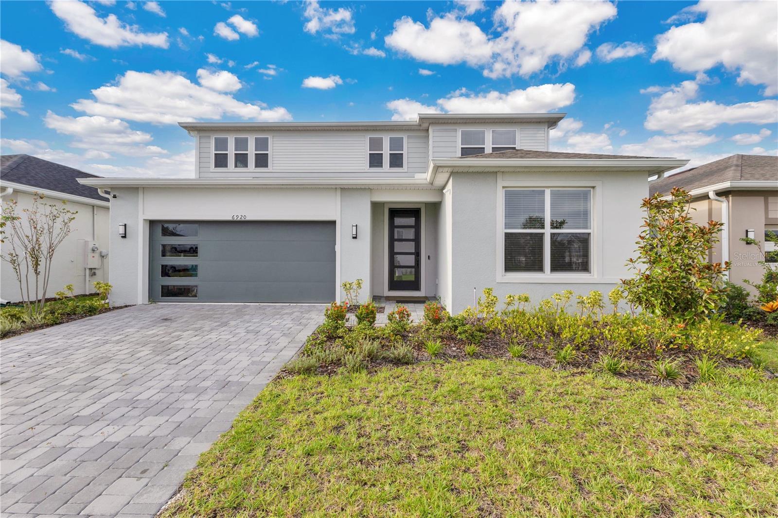 One or more photo(s) has been virtually staged. Located in Orlando’s newest master-planned community Ever Be, this 5-bedroom, 2-office, 4.5-bath, 3,777 sqft residence has been meticulously upgraded with luxury finishes throughout. The first floor features large-format porcelain tile, a gourmet kitchen with high-end KitchenAid appliances, quartz island, and abundant storage. The main living area showcases a striking stone accent wall with modern electric fireplace, while a private office on this level also includes a stone accent feature. Upstairs, new laminate flooring replaces carpet, and custom closets with built-in organizers elevate every bedroom. The master suite offers a spa-like bath with glass shower, dual vanities, and a custom walk-in closet. A garage with epoxy flooring provides parking for two vehicles inside plus space for two more in the driveway, completing the list of premium upgrades. The second floor also includes a spacious loft with a beautiful view, perfect as a family game room or private movie lounge ??. This home sits on an exclusive lake-view lot with a generous backyard ready for your dream patio design. Its proximity to the clubhouse makes it an ideal home to enjoy with family. Living in Ever Be means access to resort-style amenities such as a beach-entry pool, fitness center, splash zones, sports courts, trails, and a vibrant waterfront town center—all just minutes from Orlando International Airport, Brightline, Lake Nona, and major highways.