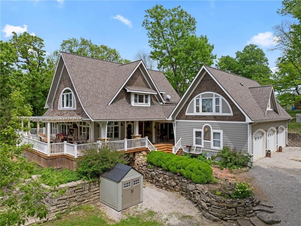 CUSTOM ESTATE HOME WITH BREATHTAKING OZARK-INSPIRED VIEWS ON 15.4 SECLUDED ACRES. Discover this one-of-a kind estate, nestled in a wooded private setting that offers stunning, panoramic views reminiscent of the Ozark Mountains. Crafted with exceptional attention to detail, the home features high-end finishes throughout, including solid hardwood and travertine floors, granite countertops and rich walnut trim directly from trees on the property. The chef's kitchen boasts a large island and open to the great room anchored by a striking rock fireplace. The main level includes a versatile bedroom or office space, while the second floor showcases a loft area and two incredible primary suites, each designed for comfort and luxury. A partially finished lower-level walk-out adds a fourth bedroom and third full bath-perfect for guests or extended family. Step outside to over 1500' of wrap-around decking, inviting you to relax or entertain while taking in breathtaking scenery. Additional private decks include 5x10 balcony off a primary suite and a 12x16 deck off the detached garage. The detached garage includes a fully finished 750 sq ft of living space with a living room, kitchen, bedroom and full bath-ideal for guests, rental income or multigenerational living. The entire property is perimeter-fenced, with iron pipe and horse fencing in the front pasture. Two outbuildings provide ample storage and utility: an 18x24 building with a loft, concrete floor and electricity and 12x24 side addition, and a 24x20 structure with 12' open overhang 10x10 milk room, concrete floors, electricity, water, and heated automatic watering tanks with insulated lines. This is more than just a home - it's a rare retreat with unmatched views, thoughtful design, and incredible amenities. A truly unique property that must be seen to be seen to be appreciated.  And the added bonus of Bates County taxes -2024 property taxes were under $3k and in Adrian school district.