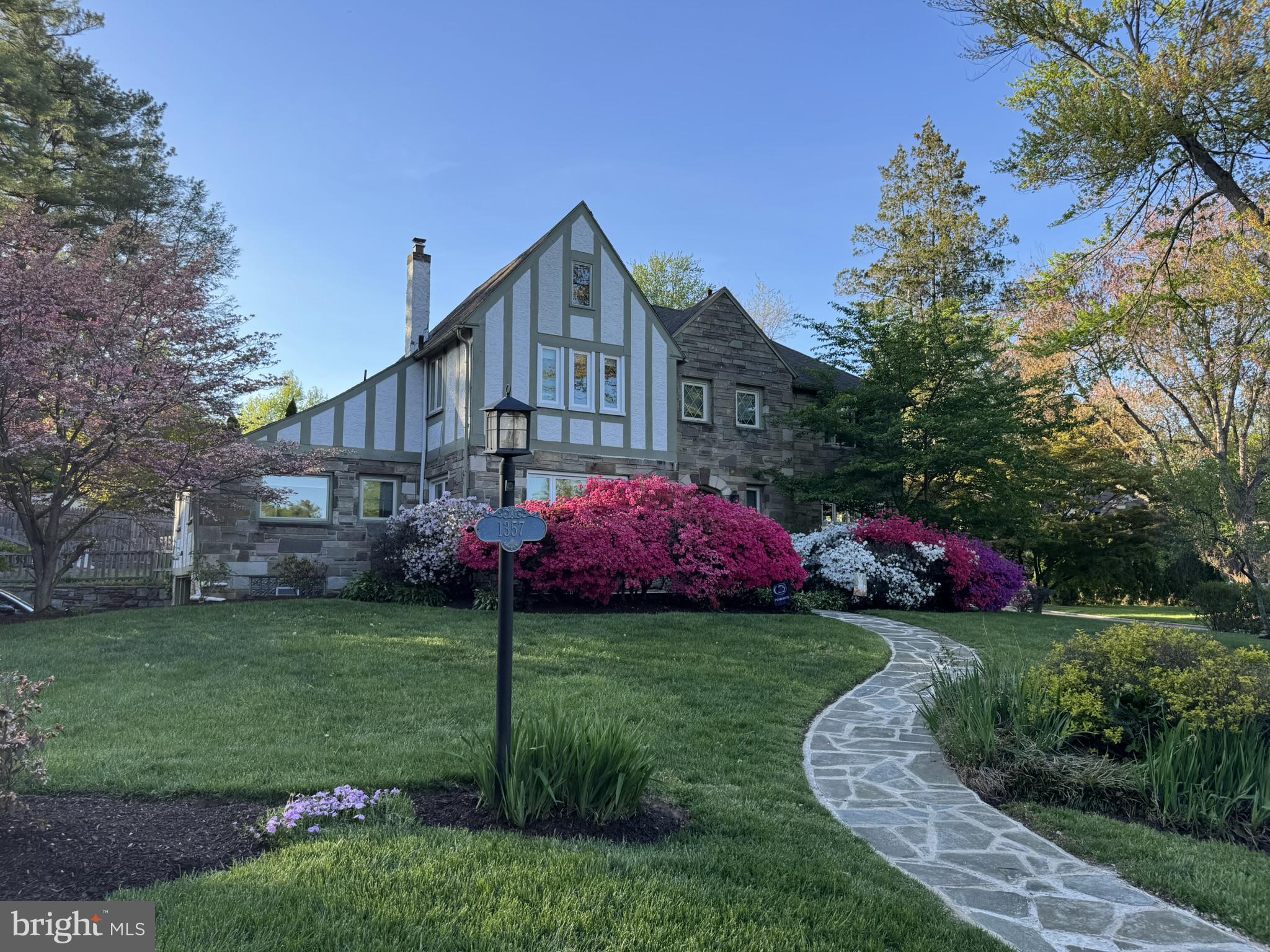 Set on a picturesque flat corner lot in Lower Merion School District, this meticulously maintained Main Line stone Tudor offers 5 bedrooms, 3 and a 1/2 bathrooms. Blending architectural character with modern amenities, this home is drenched in natural light with oversized windows and features rich hardwood floors throughout. An expansive sunken living room is perfect for entertaining, with brand new Pella windows which open for fresh air, and newer French doors leading to a covered patio, ideal for alfresco dining. The dining room sets the stage for memorable dinner parties and holiday celebrations. The centerpiece of the home is the gourmet eat-in kitchen including all stainless steel appliances, Thermador gas range and hood, under-counter microwave, GE Cafe refrigerator and dishwasher, high-end maple cabinets, and granite countertops. The main level also features a convenient mudroom which has access to the back yard and garage, laundry room, and a versatile ensuite bedroom perfect for a home office, playroom, or guest suite. A powder room off the foyer completes the main level. Ascend the curved staircase to the 2nd floor where you will find 4 generously sized bedrooms and a renovated hall bathroom. The primary suite boasts a luxurious ensuite bathroom which was recently renovated, including 2 walk-in closets. Enjoy your morning coffee on the Azek deck off the primary suite. You will also find pull-down stairs to the attic for an abundance of storage. Additional updates include newer windows throughout, a new boiler (2019), new A/C (2023) and a new roof (2026). Outside, the property is beautifully landscaped including a refinished front flagstone walkway. Alongside the covered patio, you will find a dedicated area perfect for creating your own fireside retreat. Situated just minutes from the Wynnewood Shopping Center, Whole Foods, and Suburban Square, you’ll enjoy unparalleled convenience right at your doorstep. Whether you’re exploring downtown Narberth, local dining, commuting from the Wynnewood train station, Norristown High Speed Line, or enjoying nearby Penn Wynne Park, everything you need is moments away. Close to major highways and public transportation, it’s a seamless commute to Center City Philadelphia. Complete with access to award-winning schools and a welcoming community, this move-in ready home is Main Line living at its finest.