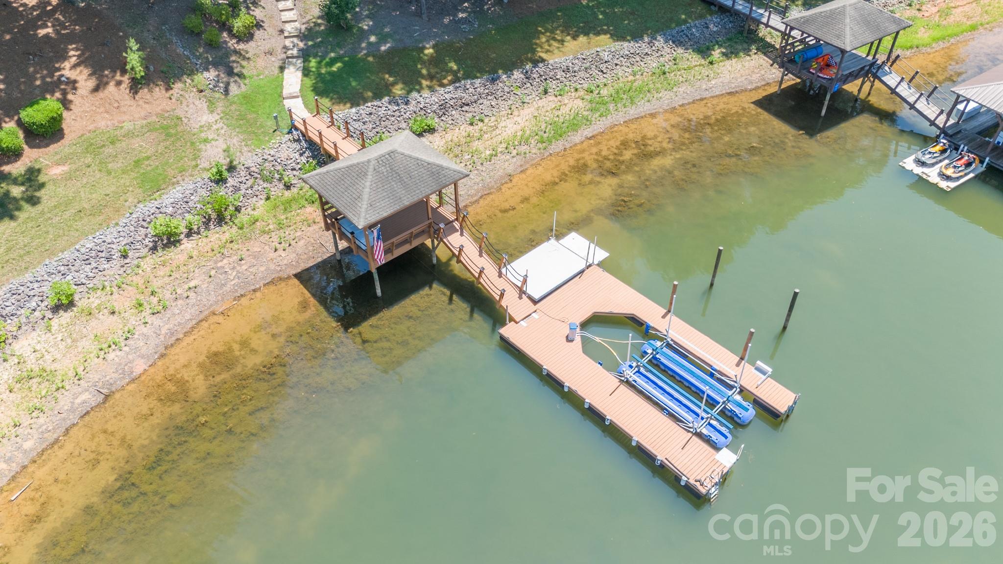 This stunning Waterfront home in the sought-after gated community of Harbor Oaks has it all. Enjoy the quiet cove sitting on your covered dock with boat lift. Beautifully updated with spacious open floor plan includes a private main-level primary suite, guest accommodations on every level and exceptional indoor and outdoor living spaces. Completely remodeled bathrooms, brand-new appliances in both kitchens, California closets in the primary suite and pantry, a new house generator, custom shutters, fresh main-level flooring and a private hot tub area with an operable roof perfect for stargazing. Split bedroom plan with private primary on main level with seating area and direct access to the recessed hot tub.  Open floor plan with great room, cozy keeping room, huge kitchen island, formal and informal dining spaces. The upper level features a bonus room with a guest suite. The lower level has abundant storage, large workshop with outside access, spacious family room, full beautiful kitchen, kitchen island, room for a pool table, seating area, guest bedroom with bath.  This home has many outdoor areas to enjoy, screened porch with fireplace, lower-level patio, outdoor kitchen, outdoor fireplace, covered seating area at the dock and front porch. Plus, fresh interior and exterior paint throughout.