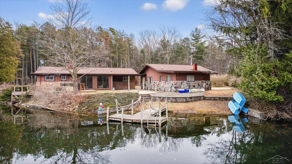 Recharge & Retreat on Raucholz!   Ready to downsize into easy, main-floor living? Dreaming of a second home that's already furnished, professionally styled, and income-ready? Or simply want a turnkey place to come home to and exhale after a long day? You just found it.  Inside this home, you'll find bright and airy spaces with vaulted ceilings and natural light pouring in, anchored by a stunning see-through, floor-to-ceiling cobblestone fireplace that connects the living and family rooms.   The kitchen and baths have been tastefully updated, featuring luxury vinyl flooring throughout the main living spaces, complemented by cozy carpeted bedrooms and the ease of main-floor laundry for added convenience.  While currently offering 2 bedrooms, there's flex space for a potential third bedroom or home office, giving you options to fit your lifestyle. And here's where it gets exciting-with a little finishing work, you could unlock a guest house setup featuring an additional bedroom, bathroom, and rec space... perfect for multi-generational living, hosting out-of-town guests, or even expanding your short-term rental potential. When it's all said and done, you're looking at the possibility of 4 bedrooms and 2.5 baths.  Outside is where this property truly shines. A 35x10 covered patio overlooks your own spring-fed pond (approx. 750x120)-fully stocked with fish and ready for kayaking, swimming, or simply soaking in the view. The hot tub + covered porch combo? That's your end-of-day reset button.  And if you're an outdoors person... this is your playground. With open field, water, and wooded surroundings, you'll find abundant wildlife, including deer and turkey-making this a true hunter's paradise.  All of this, tucked away in peaceful privacy, yet just 10 minutes to Hemlock, 15 to Freeland, and a short drive to Saginaw, Midland, and Bay City-giving you that perfect balance of seclusion and convenience.  Whether you're enjoying morning coffee overlooking the water or unwinding by the fire at night, this property delivers a