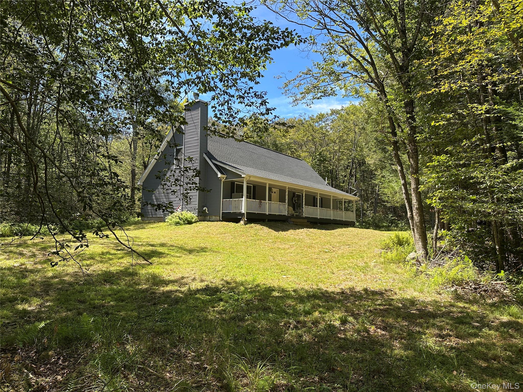View of front of home featuring a porch, a front yard, and a chimney