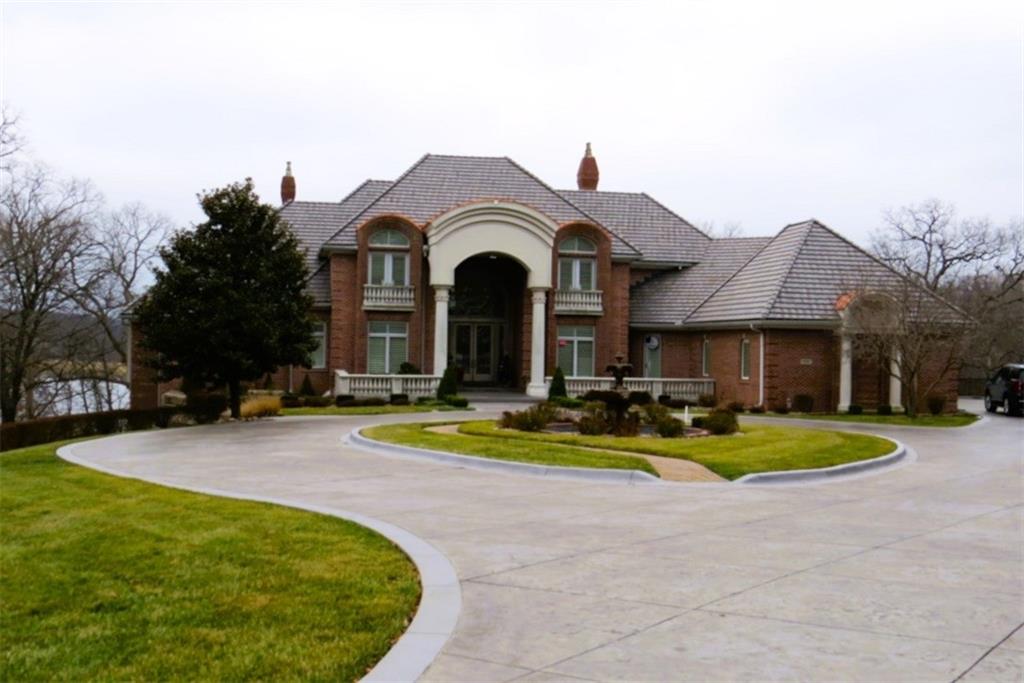 A most remarkable Home in the WEST SHORE area of RISS LAKE in Parkville, Platte County, Missouri. Relax in the Security provided by this Reserved Gated Community. You are greeted with an Impressive Circular Driveway and Stylishly Designed Home featuring an Extensive Glass Entry. The Concrete Tile Roof (replaced 2 years ago) caps a Full Brick Exterior with Coin Corners, Herringbone and Soldier Brick patterns. Inside are Soaring Ceilings on the main level with Entry Chandeliers that raise and lower for cleaning, High End Bespoke Millwork, Electric Blinds, Whole House Sound System and Custom Lighting throughout. A Suspended Curved Stainless Steel, Brass and Glass Staircase leads you from the Terrace Level through the Third Level of this Amenity Rich Home. The Theater Room, Gym, Full Bath with Steam Shower, Full Bar, Entertainment Room, Gourmet Kitchen with VIKING Appliances plus a Second Kitchen with KitchenAid Appliances on the Terrace Level bring a luxurious feel to the home. Private Office, Playroom, Covered Lanai and 11-foot Terrace Level ceilings will all add to your enjoyment of this home. This Custom-Built Home is attractively situated on a Large Estate Homesite on the Point of Riss Lake with an Expansive Deck offering an Excellent view of the 130+ Acre Lake. These Amazing Lake Views can also be enjoyed from virtually all the rear windows of the home. Upgrade your leisure time in the In-Ground Concrete Pool featuring a Waterfall, Hot Tub and SO MUCH MORE!! A must see!