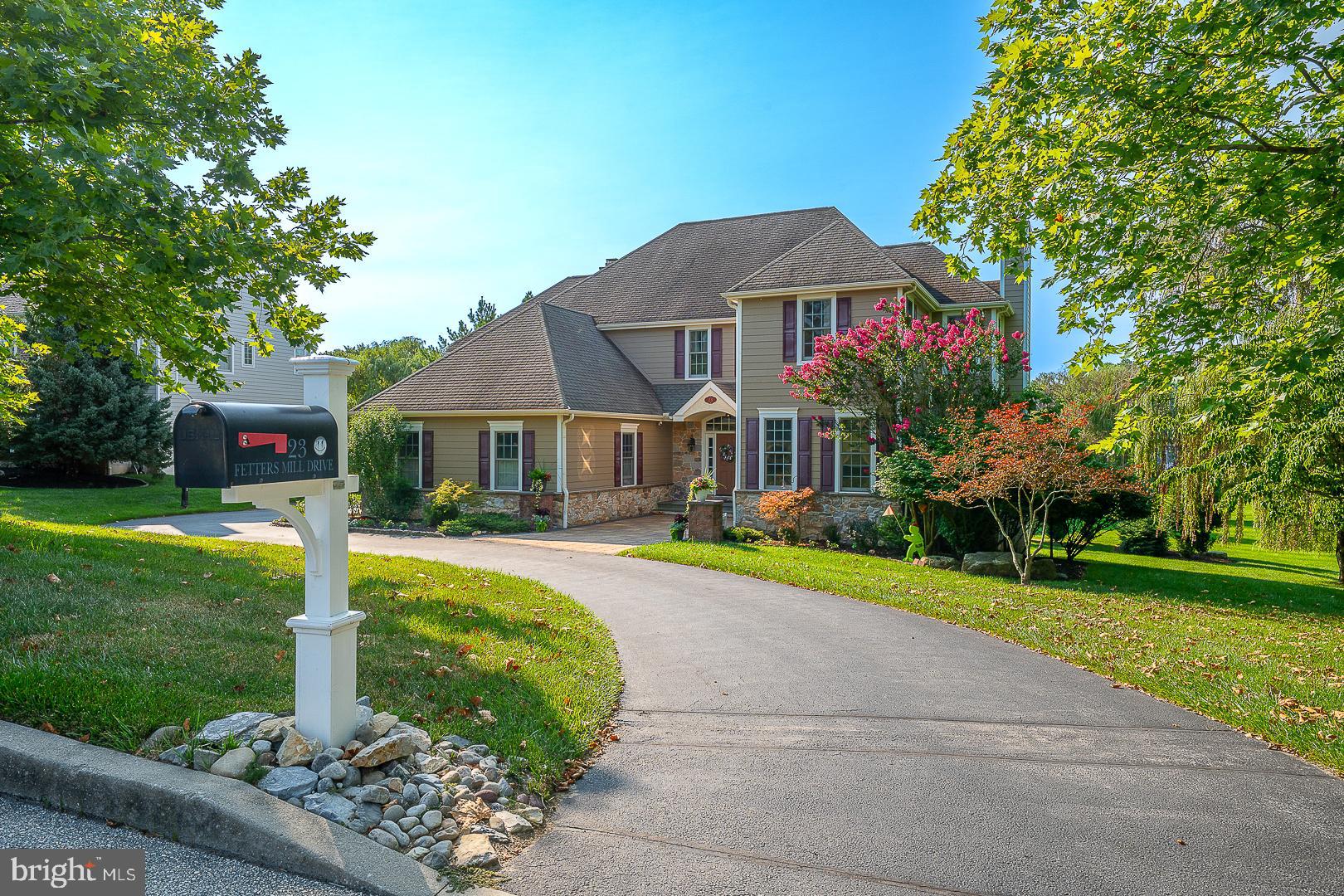 Welcome to 23 Fetters Mill Drive, an exceptional opportunity to own the distinguished Calverton Manor, a timeless custom residence in the prestigious community of Fetters Mill in Malvern. Perfectly positioned on a private homesite backing to protected open space, this remarkable property offers breathtaking views from nearly every window, complemented by mature landscaping and beautifully designed outdoor living spaces including an expansive Trex deck and paver patio that seamlessly blend with the surrounding natural beauty. Offering over 5,200 square feet of elegant living space, plus an additional 800+ square feet in the professionally finished walkout Lower Level, this impressive home features 5 Bedrooms, 4 full Baths and 1 half Bath, thoughtfully designed for both everyday living and grand-scale entertaining. A dramatic two-story Foyer with a sweeping turned staircase creates an unforgettable first impression and introduces a home defined by exceptional craftsmanship, 10-foot ceilings, rich site-finished hardwood flooring and extensive custom millwork throughout the Main Level. Elegant formal Living and Dining Rooms provide sophisticated entertaining spaces, while a private Study and versatile Flex Room with a charming Dutch door offer ideal accommodations for a second home office, library or playroom. At the heart of the home, the beautifully appointed Gourmet Kitchen is designed to inspire. Custom white furniture-style cabinetry, a generous center island with stainless sink, granite countertops, tumbled marble backsplash, built-in microwave, Thermador five-burner cooktop, professional-grade stainless steel hood and abundant workspace create a kitchen that is as functional as it is beautiful. The adjoining sun-filled Breakfast Room opens directly to the Trex deck, while the inviting Family Room features a striking slate-surround fireplace, walls of windows and access to the outdoor living areas, creating an effortless flow for entertaining and everyday enjoyment. A thoughtfully designed Mudroom offers an oversized walk-in pantry, spacious coat closet and convenient rear staircase to the second floor. The upper level features hardwood flooring throughout the hallway and includes five generously sized Bedrooms. The luxurious Primary Suite serves as a private retreat, offering a spacious Bedroom with elegant box ceiling, two walk-in closets, a private Sitting Room with wet bar, and a spa-inspired Bath featuring a jetted soaking tub, oversized walk-in shower, dual vanities and private water closet. Four additional Bedrooms include two Jack-and-Jill Baths, with two Bedrooms also featuring walk-in closets. A well-appointed Laundry Room with storage closet, built-in desk area and additional linen storage completes this level. The expansive walkout Lower Level offers soaring 10-foot ceilings and over 800 square feet of beautifully finished living space, providing exceptional flexibility for recreation, fitness, media or game rooms, along with a full Bath featuring a tiled walk-in shower, workshop space and abundant storage. Additional improvements include upgraded Hardie® Plank siding, newer HVAC systems and an oversized three-car garage. Ideally located within the award-winning Great Valley School District and just minutes from many of the region's finest private schools, Great Valley Corporate Center, the PA Turnpike, Route 202, King of Prussia, Center City Philadelphia, the Paoli Train Station, and the charming shops and restaurants of Malvern and the Philadelphia Main Line, this extraordinary residence offers an exceptional combination of timeless elegance, superior craftsmanship and an unrivaled lifestyle.