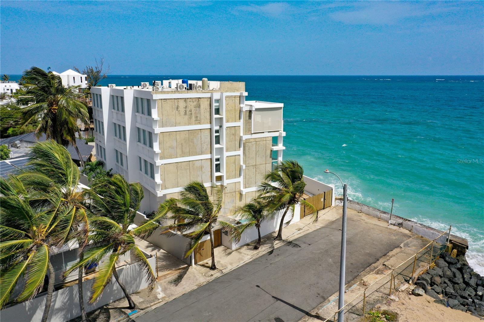Two Extraordinary Beachfront Residences | Ocean Park, San JuanA truly rare opportunity to own two spectacular residences together in the gated beachfront community of Ocean Park, one of San Juan’s most coveted gated neighborhoods. Rising directly from the sand like a waterfront castle overlooking the Atlantic, these distinctive residences combine dramatic architecture, exceptional outdoor spaces, privacy, and an irreplaceable beachfront setting.UNIT A is an architectural showpiece originally designed by renowned architect Mario Montilla and masterfully reimagined by Carlos Salazar in 2023. Spanning approximately 4,863 square feet across four levels, the residence features 5 bedrooms and 5.5 bathrooms, soaring cathedral ceilings, open-concept living spaces, and a spectacular wall of windows framing panoramic views of the Atlantic Ocean.The modern ocean-facing kitchen features quartz countertops, Smeg and Kenwood appliances, and double dishwashers. Custom oak cabinetry, a beautifully appointed bar, industrial ice maker, and beverage cooler create an ideal environment for entertaining. Multiple living areas and a flexible room with a full bathroom provide versatility for a home office, studio, guest suite, or additional bedroom.The upper levels feature luxurious primary suites with ensuite bathrooms, Grohe fixtures, custom Italian ceramic tile, double vanities, soaking tub, and steam shower. Crowning the residence is an extraordinary rooftop terrace with 180-degree beach and ocean views, complete with wet bar, grill, outdoor kitchen, outdoor shower, Vondom furnishings, and a custom electric pergola with integrated lighting and windscreen.Unit A also features a full backup diesel generator, two water cisterns, electric storm shutters, industrial-grade garage doors, and private garage parking for up to four vehicles. We added to the Private side yard a pool and tropical garden.UNIT B complements the main residence with approximately 2,700 square feet of living space, featuring 4 bedrooms and 4 bathrooms. Sharing the dramatic architectural character of its companion residence, Unit B features impressive high ceilings and a commanding beachfront presence. Its elevated design and balcony create an extraordinary connection to the ocean, while a private Jacuzzi/spa on the balcony provides the perfect setting to relax while enjoying the tropical surroundings and Atlantic breezes.Together, these residences have approximately 8,200+ square feet of beachfront living, 9 bedrooms, and 9.5 bathrooms, creating an exceptional opportunity for a luxury family compound, multigenerational residence, private retreat, or unique investment in one of Puerto Rico’s most desirable coastal communities.Located directly on the beach in Ocean Park, the property combines the tranquility of a tree-lined residential community with exceptional access to San Juan. Luis Muñoz Marín International Airport is approximately eight minutes away, while the renowned restaurants, shopping, nightlife, schools, and entertainment of Condado and metropolitan San Juan are only minutes from your door.Two residences. One extraordinary beachfront setting. A once-in-a-generation opportunity in Ocean Park.