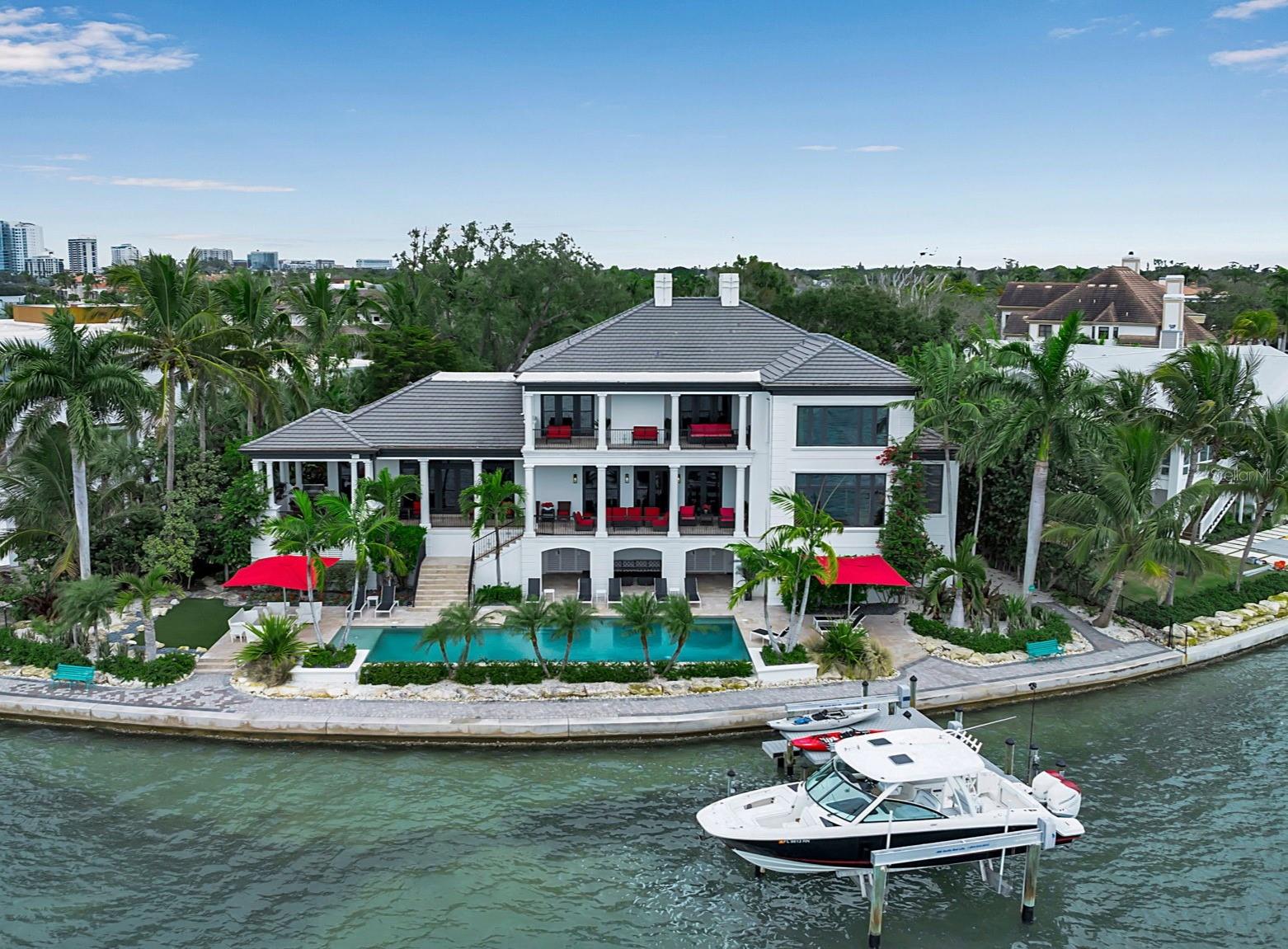 Set within the prestigious Harbor Acres neighborhood—one of Sarasota’s most sought-after waterfront enclaves, this stunningly renovated gated estate occupies an exceptional lot on the Hillview Point with 171 feet of Sarasota Bay frontage and sweeping, unobstructed panoramic views. This magnificent two-story residence, designed by renowned architect Cliff Sholz, offers six bedrooms, seven full baths, and two half baths, complemented by an oversized three-car garage—providing a seamless blend of architectural grandeur and everyday livability. A dramatic two-story foyer welcomes you inside, where expansive west-facing walls of glass capture breathtaking water vistas and bathe the home in natural light. The main level is thoughtfully designed for both refined entertaining and comfortable living, featuring a waterfront living room, an inviting family room, and an elegant dining room. At the heart of the home, the gourmet kitchen showcases authentic zebrawood cabinetry celebrated for its exotic grain patterns and rich natural character, paired with Quartz countertops, a generous center island, premium appliances, and a breakfast area with a dedicated coffee bar—perfectly suited for intimate mornings or hosting on a grand scale. Additional highlights include a private library, executive office, a full-service bar, and secondary laundry room. The owner’s suite is a serene waterfront sanctuary, offering tranquil Sarasota Bay views, dual spa-inspired bathrooms, three walk-in closets, and a private laundry—creating a truly elevated retreat experience. Ascend the sweeping staircase or take the private elevator to the second level, where five beautifully appointed guest suites provide exceptional comfort and privacy. Two of these suites, along with the upstairs library, enjoy coveted waterfront positioning and direct access to a spectacular 35-foot terrace overlooking Sarasota Bay—an ideal setting for morning coffee, sunset cocktails, or quiet moments of reflection. An additional laundry room on this level adds to the home’s thoughtful functionality. Outdoor living is equally impressive. Host unforgettable gatherings on the expansive 76-foot elevated terrace with summer kitchen or unwind poolside at the resort-style terrace featuring a 55-foot heated pool and generous lounging areas. For boating enthusiasts, private dockage delivers effortless access to Sarasota Bay and the open waters beyond. This extraordinary waterfront estate embodies the very essence of Sarasota luxury—where timeless design, exceptional craftsmanship, and unparalleled coastal views come together in a truly rare offering.