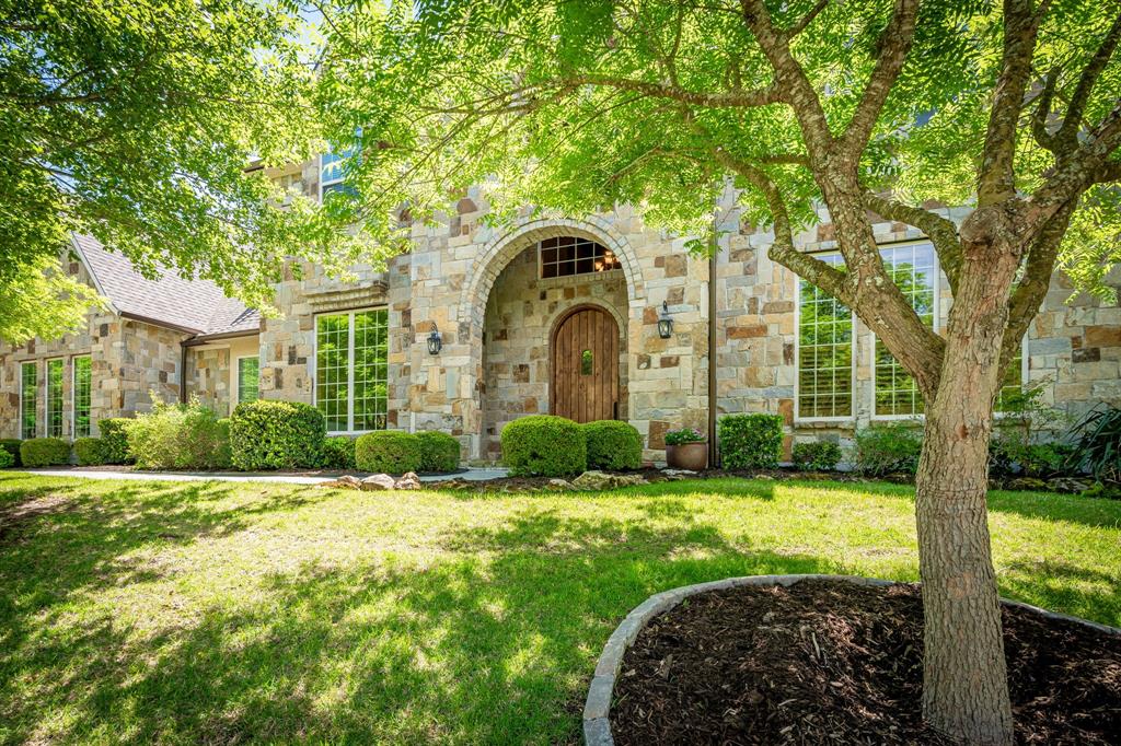 Nestled on a secluded 1.5-acre wooded lot in prestigious Creekview Landing, this extraordinary custom home offers privacy, elegance, and comfort. From the moment you arrive, the warmth of this home is unmistakable. The expansive backyard is a private sanctuary shaded by mature trees, complete with a cozy fire pit for quiet mornings, lively gatherings, and relaxing evenings under the stars. Inside, timeless craftsmanship creates an elegant yet inviting atmosphere, with knotty alder millwork, rich hardwood floors, plantation shutters, tray ceilings, and custom baseboards throughout. The family room is a stunning centerpiece featuring cathedral beam ceilings, a wood-burning gas-start fireplace, and a dramatic floor-to-ceiling stone wall. The main level includes a private office with a fireplace and built-ins, formal dining room, stylish half bath with copper sink, and media room. The gourmet kitchen features granite countertops, a large island, commercial grade Wolf gas range, triple ovens, built-in Sub-Zero refrigerator, prep sink, pot filler, and butler’s pantry with wine fridge, opening to a sunlit breakfast room ideal for daily living and entertaining. The primary suite is a peaceful retreat with patio access, custom walk-in closet, and spa-inspired bath with a backlit dome ceiling, travertine floors, and oversized multi-head rain shower. A second primary suite with patio access is ideal for guests or multi-generational living. Upstairs offers a spacious game room with wet bar, bonus room with wall of windows overlooking the wooded backyard, and three additional bedrooms, each with ensuite bath. Completing the home are a rare split 5-car garage with half bath, spray foam insulation, walk-out attic with dehumidification system, two tankless water heaters, generator, water softener, home dehumidification system, and whole-home water filtration. With remarkable craftsmanship, and a private setting, this home is a rare opportunity that won’t last long.