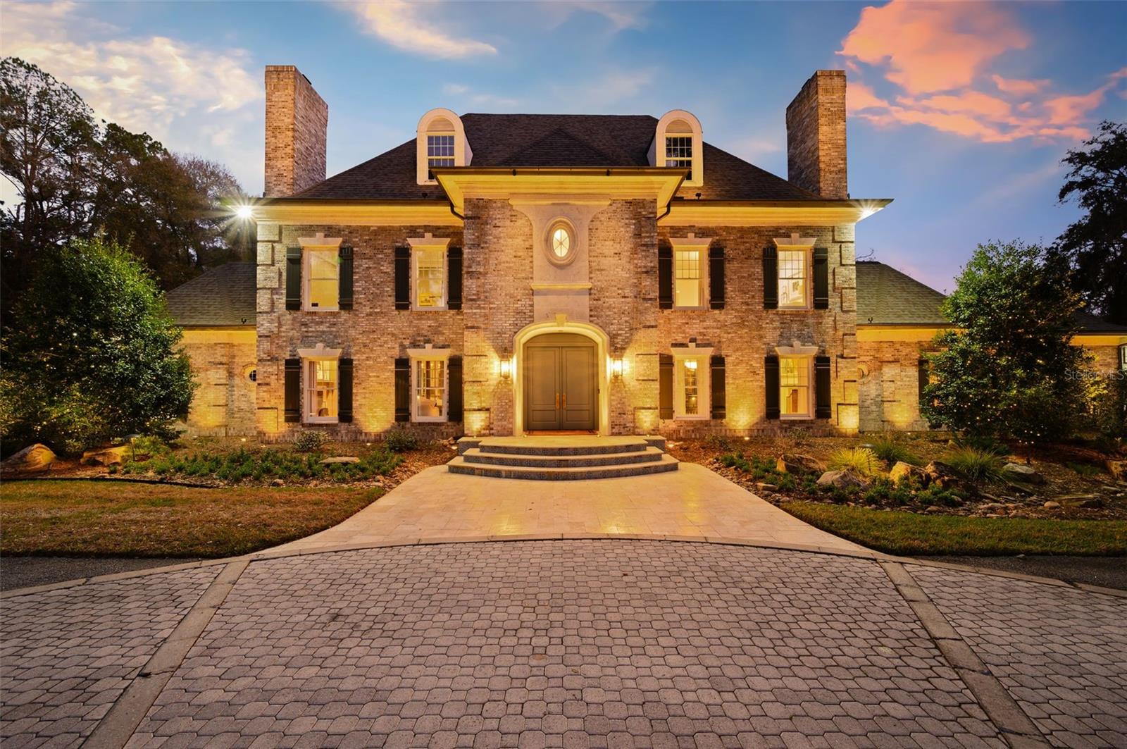Set on 6.81 secluded acres in the exclusive Tomoka Hills enclave, this extraordinary French Provincial estate offers a rare blend of privacy, elegance, and resort-style living. Exceptionally designed and spanning nearly 6,000 square feet in the main home and over 2000sf in the new guest house, the residence showcases a thoughtfully designed floor plan that flows effortlessly for both comfortable daily living and sophisticated entertaining.Remodeled by local custom builders, the home features impeccable craftsmanship and high-end custom details throughout, reflecting remarkable attention to fit and finish. The main residence includes four spacious bedroom suites, all en suite, along with 5.5 bathrooms.Inside, gorgeous hardwood floors unify the entire home while a dramatic two-story foyer with intricate woodwork welcomes guests and frames immediate views through French doors to the pool and completely private backyard. The first floor offers multiple gathering spaces, including a sitting room with fireplace, formal dining room that flows through a Butler's Pantry to the kitchen and a spacious family room with a nearby half bath and wine bar—ideal for entertaining.The luxurious primary wing serves as a private retreat, featuring a sitting room (or office), a spa-inspired bath with a free standing tub, separate marble vanities, and a large walk-in shower finished in Calacatta marble with rain shower head and multiple shower heads. A large dressing room with an extensive organizational closet system completes the suite.Designed with entertaining in mind, the formal dining room connects to the stunning chef’s kitchen through a separate butler’s pantry, providing the perfect space for catering prep and seamless hosting. Upstairs, a gracious landing with open-air balcony access leads to three additional private suites, plus a flexible bonus room with built ins.Adding tremendous value and versatility to the property is a newly constructed 2,100-square-foot detached guest house. This luxurious residence offers two bedrooms (one BR is currently used as a GYM with rubber mat flooring), one bathroom, a spacious living room, and a full high-end designer kitchen with premium finishes. Perfect for guests or extended stays, the guest house also features a large summer kitchen with motorized screens, creating a seamless indoor-outdoor living experience that flows beautifully to the resort-style pool area. With its designer finishes, spacious layout, and luxurious feel, this guest residence functions as a private retreat within the estate.This remarkable property combines refined European-inspired architecture, modern luxury updates, and expansive grounds, creating a truly exceptional estate setting located in a prime location in SW Gainesville.