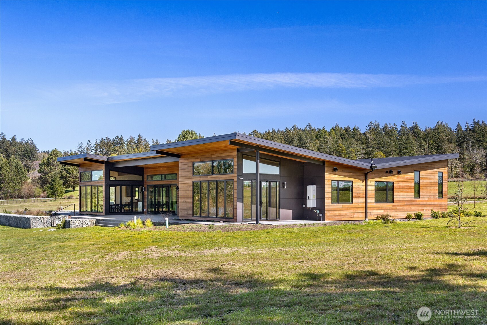 Refined living near beautiful False Bay—this is a rare opportunity to own a newly built modern estate on 8± private acres in the sought-after Gleneagle neighborhood. Completed in 2023, the home combines clean, contemporary design with timeless craftsmanship, all set among open skies, west-facing views, and peaceful island privacy.  The 3,372 sq ft main residence features three en-suite bedrooms, five bathrooms, and a dedicated office, offering a layout that works just as well for daily living as it does for entertaining. At the heart of the home is an open-concept living space anchored by a chef’s kitchen with high-end appliances, custom cabinetry, and quality finishes throughout.  Expansive windows fill the home with natural light and frame serene meadow and sunset views, along with a picturesque outlook across common land featuring a pond, gazebo, and small dock.  A separate 786 sq ft guesthouse provides flexible space for visitors, extended stays, or a private studio—while preserving privacy for both homes.  Modern San Juan Island living at its best—new construction, thoughtful design, and a quiet, scenic setting just minutes from Friday Harbor’s shops, dining, and marina.