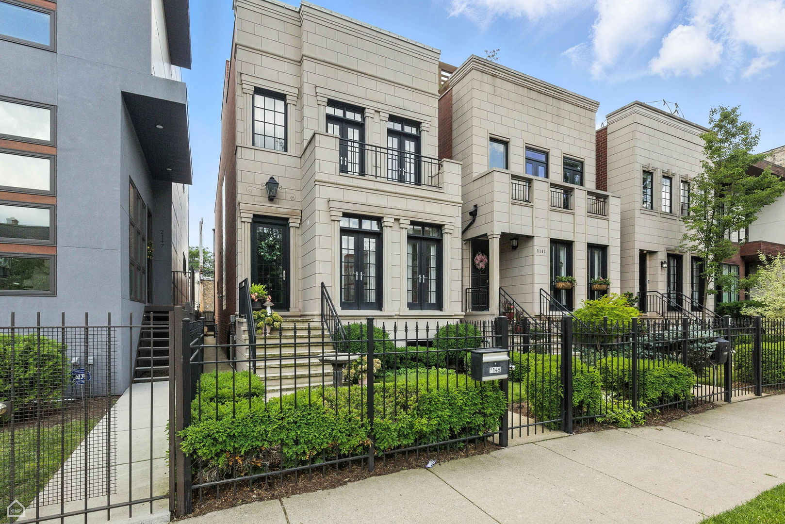 Welcome to 2149 W Huron, a 4-bedroom, 3.1-bath brick and limestone single-family home offering nearly 4,200 square feet of thoughtfully designed space across three expansive levels. This custom residence blends urban design with refined luxury in one of West Town's most desirable enclaves-just steps from Smith Park and within the coveted Mitchell School District. The classic limestone facade with black-clad windows sets a sophisticated tone, enhanced by custom lighting and a striking glass-block feature wall. Inside, a floating steel staircase anchors the open-concept main level, where walls of oversized windows, custom window treatments throughout, and tall ceilings flood the home with radiant natural light. A grand dining room with a dramatic two-story vaulted ceiling flows into the formal living space, centered around a modern stone fireplace-one of three fireplaces in the home, including a wood-burning fireplace in the living room, and ventless gas fireplaces in both the primary bedroom and the lower-level family room. The heart of the home is a chef's dream kitchen, meticulously appointed with a 60" Viking range, Northland Master Series refrigeration, quarter sawn oak cabinetry, and marble countertops. Unique custom additions include a built-in vegetable and pasta steamer and an event beverage trough, designed for effortless entertaining. A functional island with open shelving, ample prep counters, and sleek designer lighting elevates the experience. The adjoining butler's pantry includes a U-Line ice maker, second sink, and additional dishwasher, ideal for hosting. Upstairs, two dual-suited bedrooms showcase sophisticated design. The south-facing primary suite is a serene escape featuring a wood-accented feature wall, chandelier, and private sitting area with a cozy fireplace. French doors open to a secluded balcony, while dual walk-in closets lead to a spa-inspired bath with a sunken air tub, heated floors, and an oversized shower. The secondary suite offers a walk-in closet and a beautifully finished bath with standalone shower, stone surfaces, custom vanities, and matte black fixtures. The lower-level impresses with a walk-out family room featuring custom built-ins, a third fireplace, and a full wet bar with glass-front cabinetry-plus direct access to a private brick courtyard. Two additional bedrooms, a full bath with open-concept shower, and a large laundry room with dual washers and dryers complete the space. This home offers multiple outdoor areas, including a main-level terrace, private terraces off the primary suite and lower level, and interior stair access to the roof-fertile ground for future rooftop deck plans. The professionally maintained irrigation system keeps all landscaping lush and thriving. Tech and lifestyle amenities abound with a whole-home AV system, built-in speakers, and all AV equipment included-perfect for modern living. Ideally located within blocks of Metra, Mariano's, I-290, and Chicago Avenue's vibrant dining scene. Just down the street, Smith Park provides a community anchor with community center & pool, tennis and pickleball courts, a splash pad, playground, and open green space.