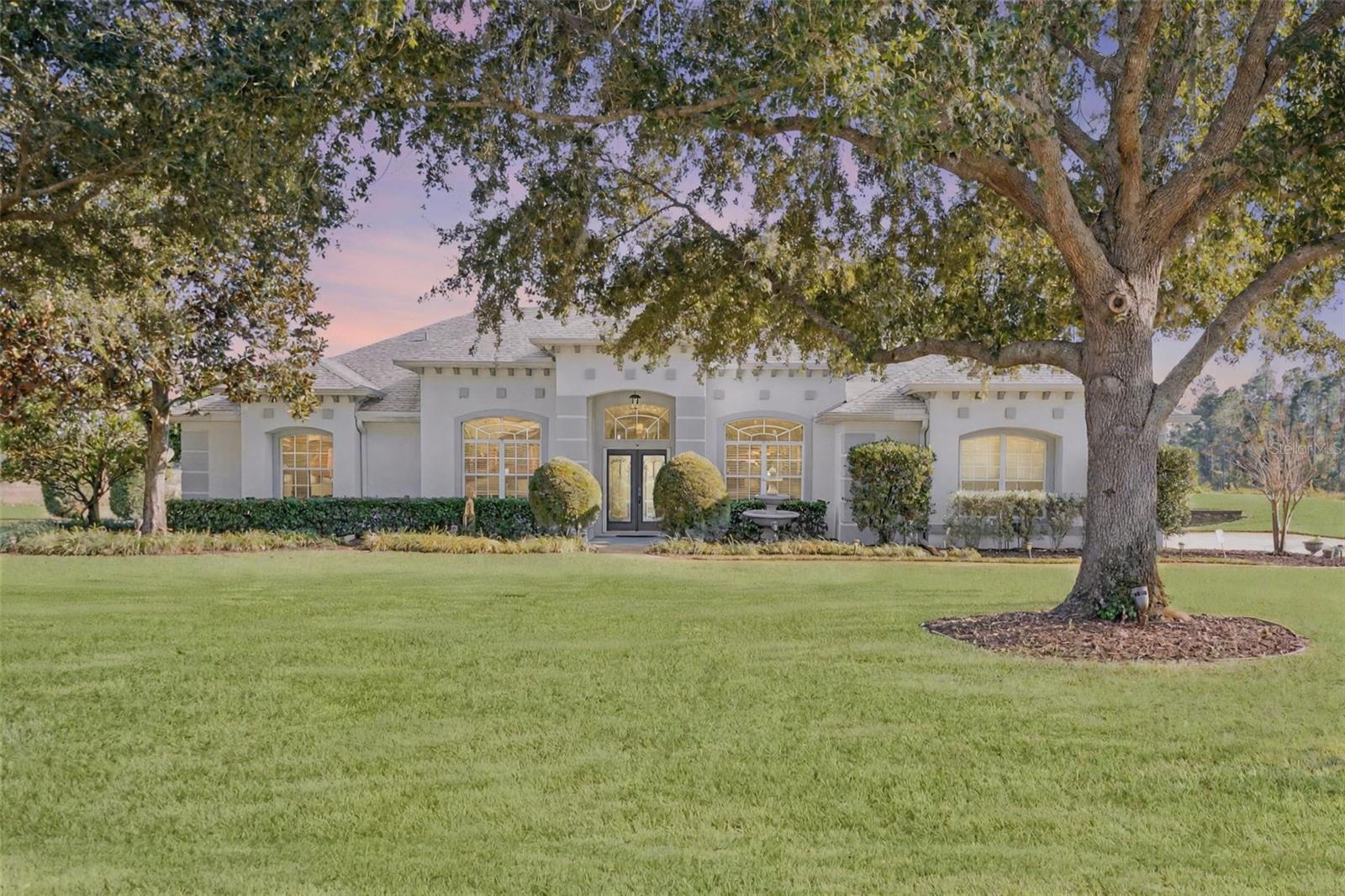 Under contract-accepting backup offers. Beautiful and meticulously maintained, this stunning 4 bedroom, 3 bath pool home sits on over 1 acre in the highly desired Arrowtree Reserve. This spacious tri-split floor plan features a screened pool, outdoor kitchen, and gorgeous waterfront views that create the perfect indoor/outdoor lifestyle. As you enter, you’re greeted by a formal dining room and dedicated office/den, flowing into a bright kitchen with quartz countertops, and views into the family room. Brazilian hardwood floors run through the main living areas, complemented by beautiful wood ceiling beams, fireplace, and thoughtful details throughout. The large primary suite offers peaceful pool and water views, a spa-like bathroom with dual vanities, fireplace, a soaking tub, a large walk-in shower, and an expansive custom closet with built-in organizers. The 4th bedroom functions as an ideal guest or in-law suite with its own full ensuite and convenient pool bath. Outside, enjoy sunrise over the water from the pergola, or relax under the spacious screened lanai. Additional highlights include an oversized side-entry 3-car garage, tons of storage, a newer roof (2020), AC (2018), heat pump (2021), and a beautifully maintained 1+ acre lot. Located just minutes from Hwy 19 and the turnpike, this home checks all the boxes for comfort, beauty, and convenience. *Aerial photo property lines are an estimate and to be verified by buyer.