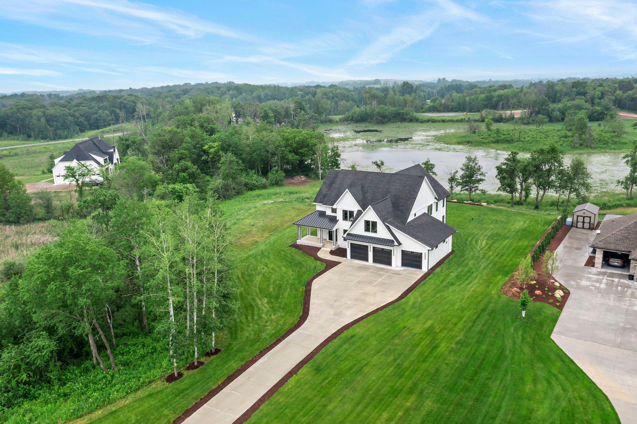 Exceptional custom-built home on 3.47 acres in Lakeville, offering luxurious design and everyday comfort in a serene acreage neighborhood. The main level features a dramatic great room with 18-ft vaulted ceilings, wood beams, hickory hardwood floors, and a floor-to-ceiling tiled fireplace. A chef’s dream kitchen boasts quartz countertops, a professional gas range, custom panel appliances, an oversized island, and a walk-in pantry with a full fridge and prep space. Enjoy panoramic pond views from the dining room, or relax year-round in the cozy 4-season porch with a gas fireplace. Upstairs, the spacious primary suite includes 11-ft vaulted ceilings, a spa-like en-suite with dual vanities, private commode, expansive walk-in closet with custom built-ins, and direct access to the laundry room with a dog wash station. Three other additional bedrooms on this floor offer walk-in closets and ensuite or Jack-and-Jill bathrooms. The finished lower level is designed to entertain with 9-ft ceilings, a large family room, wet bar with quartz counters, wine fridge, and built-in speakers. A sixth bedroom and ¾ bath complete the space. The fully finished, heated 3-car garage includes 11-ft ceilings, epoxy floors, and EV charger rough-in. Smart features include Sonos audio, Ring doorbell, Swann security system, smart mirrors, and full water filtration. Professionally landscaped with irrigation, Hardie siding, and steel roofing over the porch and garage. All just minutes from I-35W—luxury country living at its finest!