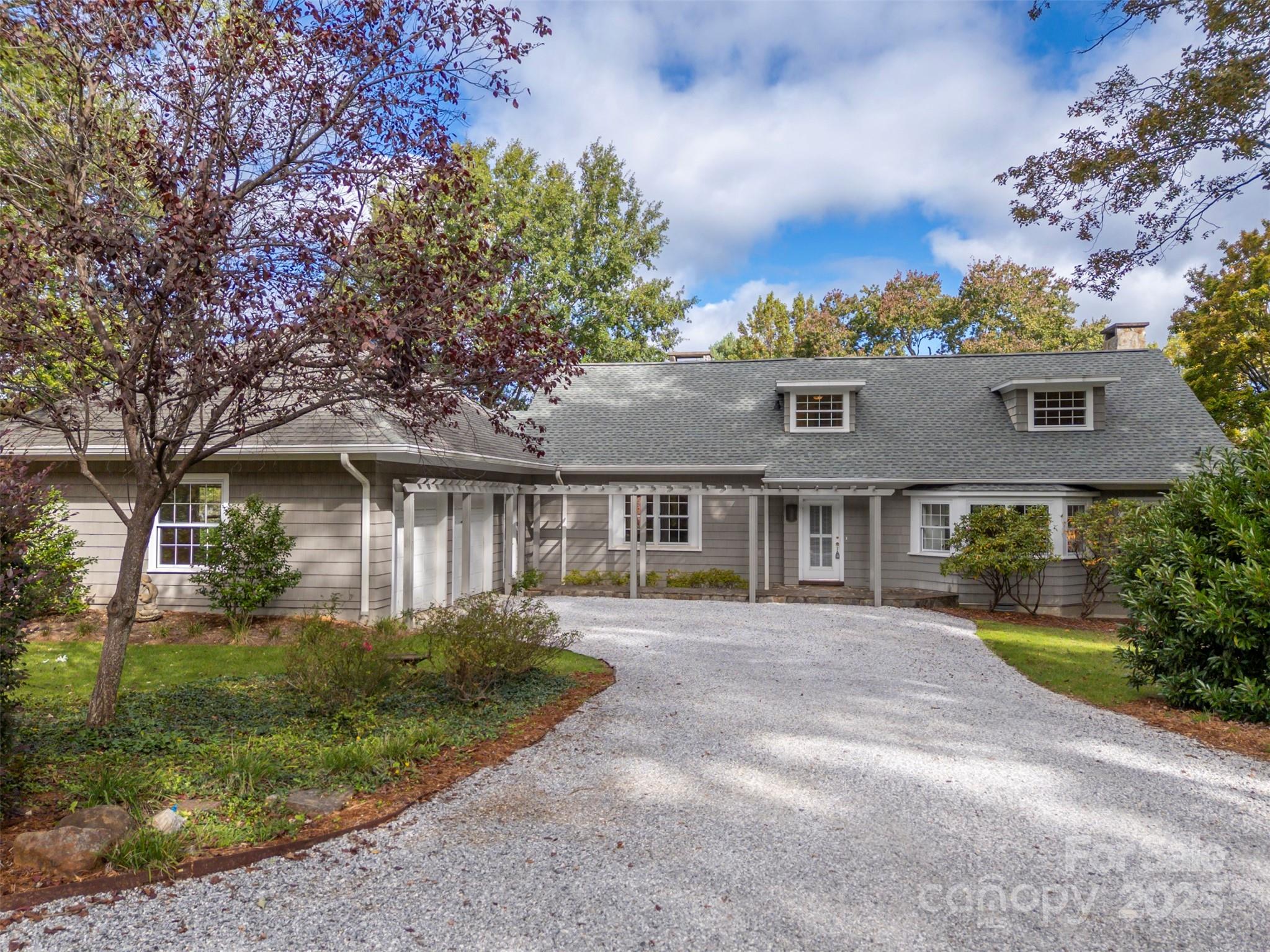 Enjoy luxury framed against the mountains on a quiet cul-de-sac street, easily walkable into downtown Tryon. One-level life easy with master, large living room, dining, all-seasons room, office and laundry all on first floor. Year-round mountain views, set against ancient oaks, looking over the roof of the historic Pine Crest Inn. Tryon Peak and Warrior seen year round. Howard Gap and Warrior come into winter view. Spectacular entertaining kitchen added with spacious garage in 2011 addition. Fireplace in master, living room and all seasons room. Wood and original cork flooring. Upstairs bedroom windows configured for views in prior owners' art studio. Whole-house Kohler generator as well as water and stove are all on natural gas. Heated exercise room in large, unfinished basement with space for second living quarters and separate entrance. There's a carport and drive around the side for extra vehicles. Security system in place. Roof just three or four years old. Mature landscaping and rock work complete the foreground beauty of this one-of-a-kind property.
