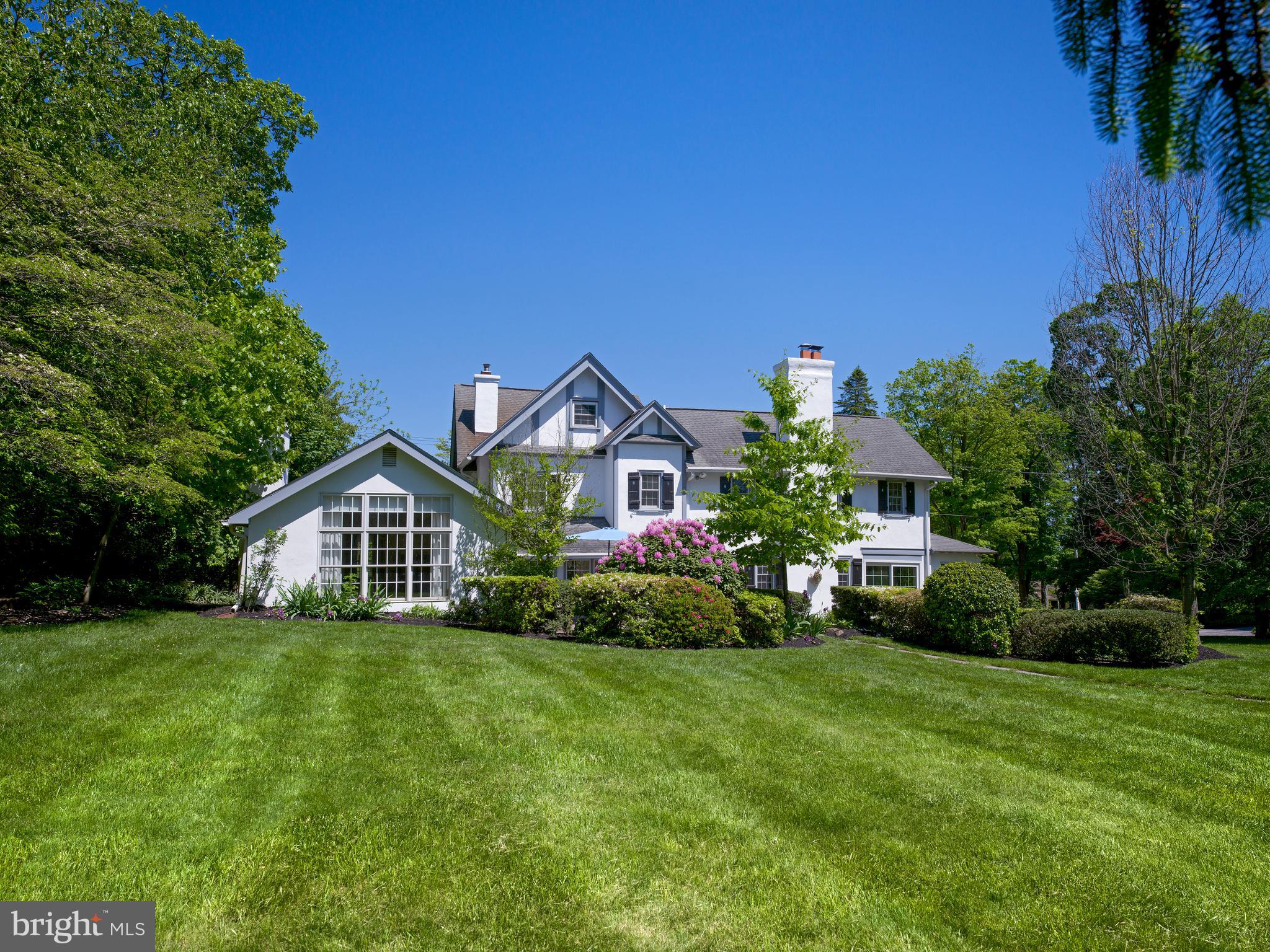 A distinguished South Devon residence set on 1.2 beautifully landscaped acres in the award-winning Tredyffrin-Easttown School District. White stucco with Tudor half-timbered gables and period detail throughout reflect more than a century of careful stewardship. Over generations, the late-19th century core stone structure has been thoughtfully modified and expanded multiple times while maintaining its original character and sense of history.The original portion of the home now contains a gracious dining room, kitchen, and butler’s pantry. A 1927 expansion added a comfortable living room and porch, subsequently revised to incorporate a bright sunroom. Another expansion in 1985 added a large and functional family room along with a reconfigured kitchen. The home offers five bedrooms, three and a half baths, and a full basement.Other notable features include three wood-burning fireplaces, natural gas hot water heat, a Generac generator, upgraded Pella windows, a Thermador double oven with side-opening doors and rotisserie and a shower in the primary bath with steam. The property also includes an original carriage house offering flexibility for a variety of uses.The grounds are a highlight: established perennial gardens, flagstone terraces, specimen plantings, stone walls, and open lawns framed by mature trees and English Hurdle fencing.Minutes from the Devon train station, the Route 30 corridor, and the shops and dining of the central Main Line.