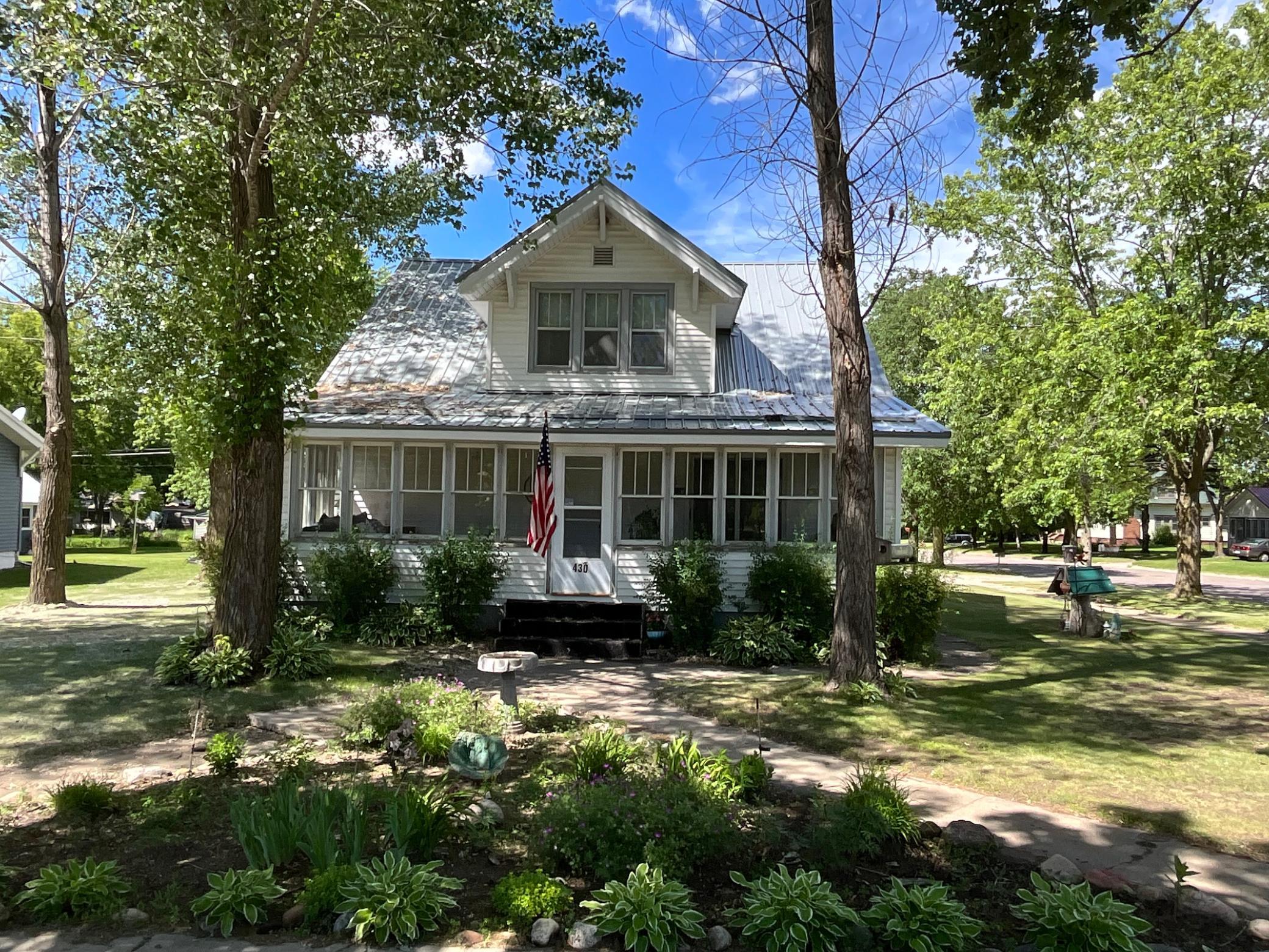 Charming 3-bedroom, 2-bath home, filled with character and thoughtful updates. An enclosed front porch with large windows welcomes you inside, offering a cozy spot to enjoy morning coffee or evening sunsets.The home features new kitchen cabinets, a new hot water heater, and several updates already completed, while still leaving room for your personal touch to make it truly your own.Outdoors, the property shines with many established perennials, an extra-large garage, and a steel roof on both the home and garage for long-lasting durability. Enjoy relaxing evenings in the outdoor hot tub, and take advantage of the convenient space to park a camper.Situated on a desirable corner lot, this property blends historic charm with modern comfort—an inviting place to call home with plenty of potential to grow.