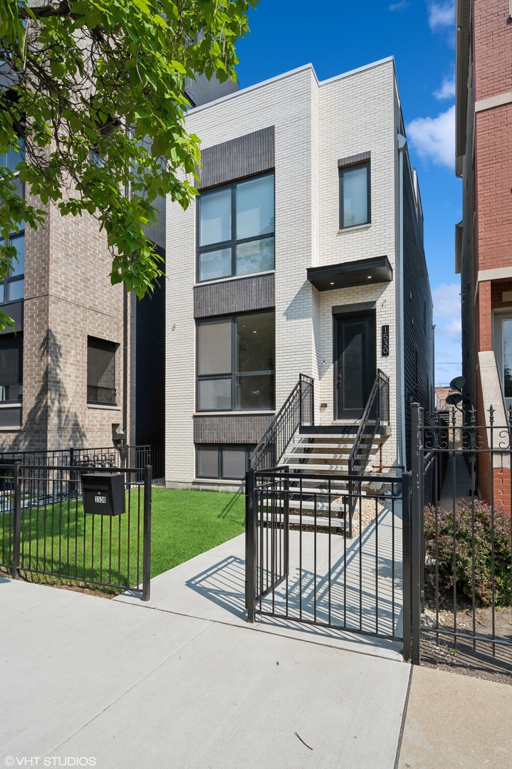 Newly constructed in 2023, this elegant single-family home in West Town seamlessly blends modern luxury with functional design. This 5-bedroom, 4.5-bathroom residence features a full rooftop deck, a garage deck, and a spacious grass front yard and backyard. Lumini windows and 6.5-inch wide-plank hardwood floors enhance the interior's sophistication. The open floor plan showcases a bright, south-facing living and dining area with a quartz-surround fireplace. The gourmet kitchen boasts high-end Thermador appliances, Brizo fixtures, and a large quartz island. Post-construction upgrades include high-end motorized window shades, custom closets, and dual HVAC systems for year-round comfort. The second floor offers three bedrooms, each with en-suite bathrooms, and a convenient side-by-side laundry closet with a countertop. The primary suite features two spacious closets and a spa-like bathroom with an extended double vanity, heated floors, a freestanding soaking tub, and a multi-jet glass shower. The lower level includes two large bedrooms, a recreation room with a den and wet bar, a full bathroom, extra storage, and an additional laundry hookup. The recreation room's den, enclosed by barn doors, provides versatile space for an office, gym, or guest room. Ideal for entertaining, the home features a stunning rooftop deck with skyline views and a backyard perfect for grassy turf or a paved patio. A two-car garage with an additional deck expands outdoor living options. Located in vibrant West Town, steps from West Loop, this home is surrounded by top-tier restaurants and boutique shops.