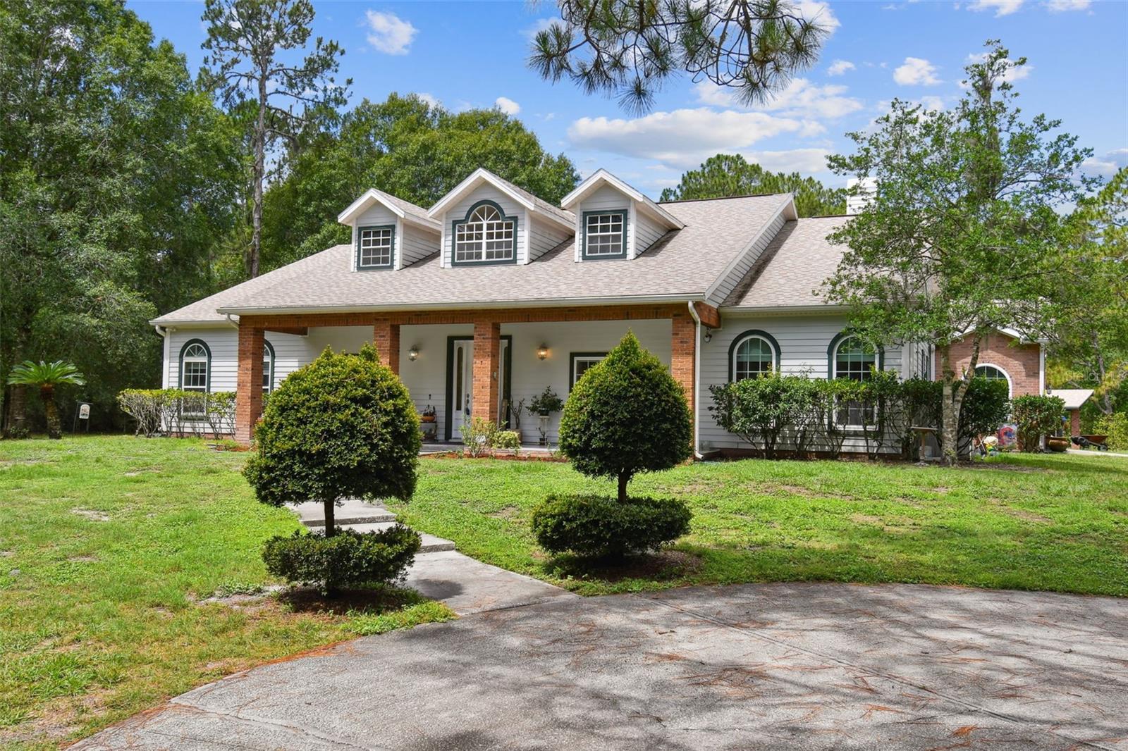 Welcome to 28606 Credence Drive.  If you are looking for big city convenience with the peace of living in the country, then come and enjoy this Custom Single Story Home in the heart of Wesley Chapel. Situated on a 2.1-acre lot, this MOVE-IN READY home is perfect for entertaining, hosting guests, or raising a family.  The gated entrance and circle driveway will take you through a mature, landscaped property with lots of privacy. Upon entering your new Florida homestead, you will see a stately farmhouse exterior featuring a wide front porch, brick trim and dormers.  Inside, you'll discover a modern 3-way split floor plan.  In the expansive owner's bedroom, there is plenty of space with an ensuite. The Owner's bathroom features a double vanity, walk-in shower, and a soaking tub, perfect for relaxing in after a hard day. A second bedroom also features a newly remodeled ensuite.  The third bedroom on the other side of the home is right next to the remodeled third bath and the laundry room. This bedroom and bath arrangement assures maximum privacy and the convenience of a separate bath for each bedroom.  To the left of the entry, you will find a Formal Living Room with built-ins, lovely double French doors and a third French door right around the corner.  This space is great for a private conversation or for reading a good book and is perfectly set up to be used as an office if needed. On the right is a Formal Dining Room leading to the Kitchen, where you will find handsome wood cabinetry, granite counters and a matching breakfast nook table which stays. The breakfast nook overlooks the 37' x 23' lanai. The Great room invites you to sit and entertain with its built-in shelving, gas fireplace and French doors leading to the caged lanai. Inside the home, some of the wood flooring, all the doorknobs and locks have been updated and most rooms have been updated with new ceiling fans and LED lighting. New windows in 3rd bedroom and on North side of house.  A garage conversion has a separate HVAC system and flex space options might include:  home office, party room, catering space, craft space, home school, pet care or even a fourth bedroom.  Outside you will want to just relax and enjoy the bug-free view from the rescreened, caged lanai to your natural Florida acreage.  The well-built 1,300 (approximately) square foot detached garage has plenty of space upstairs and downstairs for toys or could make the perfect workshop.  Experience peace of mind with the Briggs & Stratton Fortress WHOLE HOUSE GENERATOR with above and below ground fuel tanks.  No matter the weather or power outages, you will always have a reliable source of electricity.  All buildings on the property had a NEW ROOF in 2020.  Concrete block home's exterior has durable, long-lasting and low-maintenance fiber cement siding. This is a wonderful opportunity to own a luxury home in Quail Hollow, known for its custom homes on acre lots.  Close to restaurants, shops, medical facilities, malls, parks and excellent schools, this beauty is in an ideal location with every desirable amenity close by and with easy access to Interstate for commuters!  Zoning permits farm animals, including horses!  There are no restrictions, HOA or CDD fees!  This home is a must see, schedule your private tour today.   NOTE:   A portion of the existing fence on North Side is not on the property line and encroaches on the 1.6-acre adjacent property which is also for sale for $189,000.  MLS#T3448873