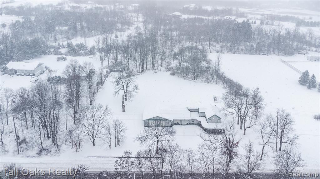 Welcome to this stylish remodeled farmhouse that blends classic charm with modern updates on over 6 acres in the heart of Goodrich. Offering over 2000 sq ft, this home includes 3 bedrooms and 3.5 bathrooms with quality improvements throughout. The updated kitchen features concrete countertops, commercial-grade appliances, a walk-in pantry, abundant cabinet space, and an electric fireplace. The first-floor primary suite provides privacy and comfort with heated slate flooring, a slate walk-in shower, and a soaking tub to enjoy. First-floor laundry adds everyday convenience. A major highlight of the property is the oversized 6-car garage—large enough to fit up to 8 vehicles. This space includes heated floors, its own furnace, and a full bathroom with shower, making it ideal for car collectors, contractors, or hobbyists needing functional workspace. Recent mechanical upgrades include a new furnace and 5-ton AC installed in 2021. The home also features a wrap-around porch, offering the perfect spot to relax and enjoy the peaceful surroundings. The property sits on over 6 acres, offering privacy, wooded area, and frequent wildlife. Close to Goodrich amenities and next to the high school, this home provides land, character, and convenience without village taxes. Homes with this level of updates, acreage, and garage space are hard to find.