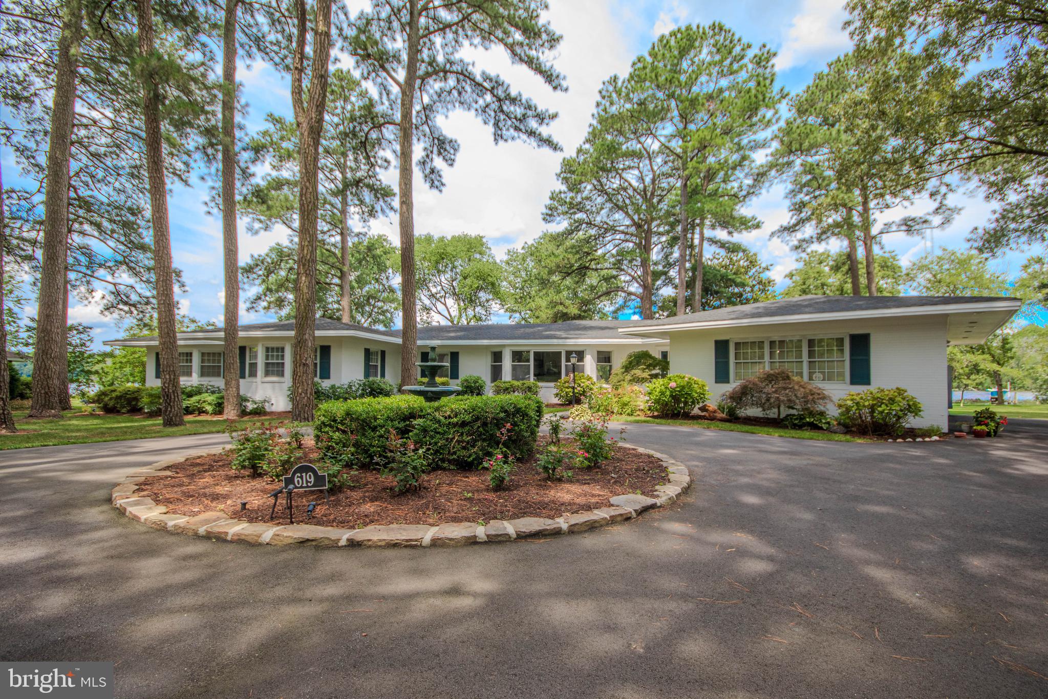 Welcome to 619 Ridge Road, a stunning waterfront retreat offering 4 bedrooms, 3 full bathrooms, and 2 half bathrooms on 1.64 beautifully landscaped acres within the city limits. Perfectly positioned along the Wicomico River with nearly 300 feet of water frontage, this exceptional property captures breathtaking river views from virtually every rear-facing room. Designed with both comfort and functionality in mind, all bedrooms are situated on one end of the home, creating a private living wing. The spacious primary suite serves as a true sanctuary, featuring panoramic river views, an elegant ensuite bath with heated tile flooring, a tiled walk-in shower, dual vanities, a dedicated makeup vanity, and a private door leading directly to the hot tub, which conveys with the property. An adjoining office offers the ideal work-from-home setup and is accessible from both the primary suite and the main hallway. Hardwood flooring flows throughout the home, while oversized windows flood the interior with natural light and showcase the spectacular waterfront setting. The open-concept kitchen is designed for gathering with a fantastic gas range, stainless steel appliances, an attached dinette, and seamless flow into the spacious dining area. To complete the kitchen, you'll love the additional counterspace and prep sink that the separate island features. Multiple living spaces include a welcoming front den and an expansive main living room, providing plenty of room for entertaining or relaxing. A generously sized laundry room with a folding station connects to the attached two-car garage for added convenience. The outdoor spaces are every bit as impressive as the interior. A large deck overlooks the expansive backyard and leads to a beautiful paver patio, creating multiple areas to relax and entertain while taking in the peaceful riverfront setting. The wraparound asphalt driveway makes an elegant first impression, centered around a striking sculptural water feature that serves as a stunning focal point upon arrival. Meticulously maintained landscaping enhances the beauty of the property from every angle. Nature lovers will appreciate the abundance of wildlife that calls this stretch of the Wicomico River home. Spend your mornings watching graceful herons along the shoreline, majestic bald eagles and osprey soaring overhead, and, in the evenings, listen for the distinctive call of the great horned owl—an everyday reminder of the property's remarkable natural setting. For boating enthusiasts, the property features a shared dock walkway while offering the privacy and convenience of its own dedicated boat lift, providing easy access to the Wicomico River whenever adventure calls. This is a rare opportunity to own an exceptional waterfront home where timeless design, thoughtful amenities, and spectacular views come together in one remarkable property.