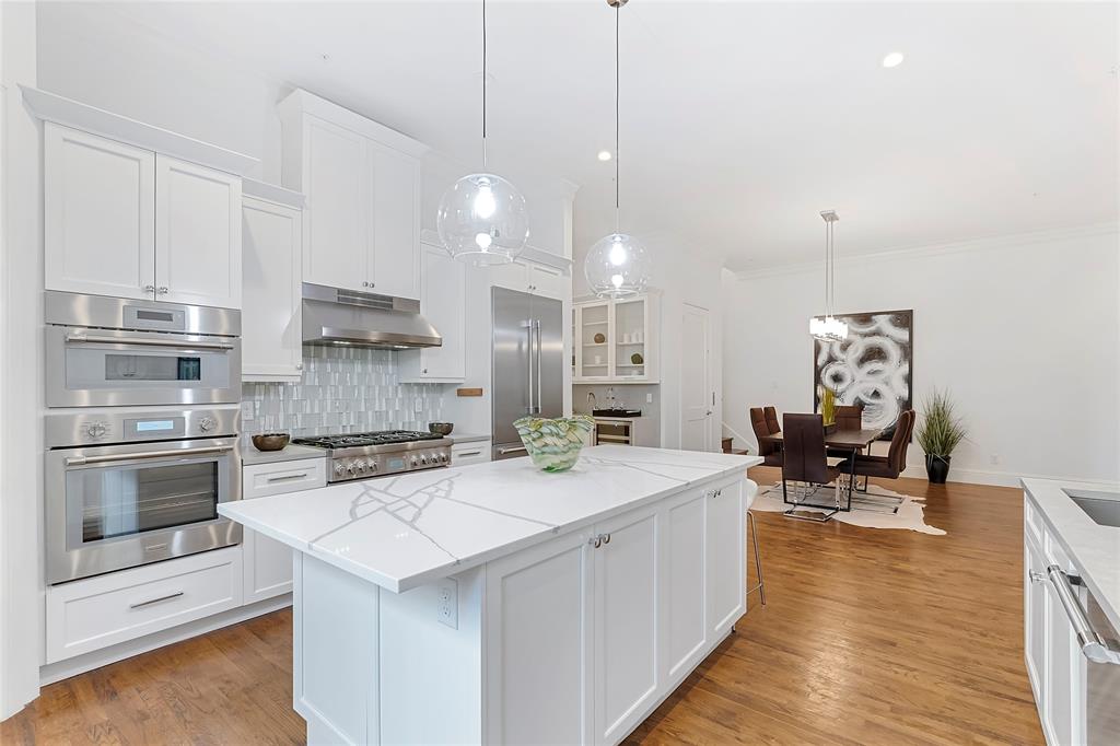 Kitchen featuring white cabinetry, a kitchen island, hanging light fixtures, and light hardwood / wood-style flooring