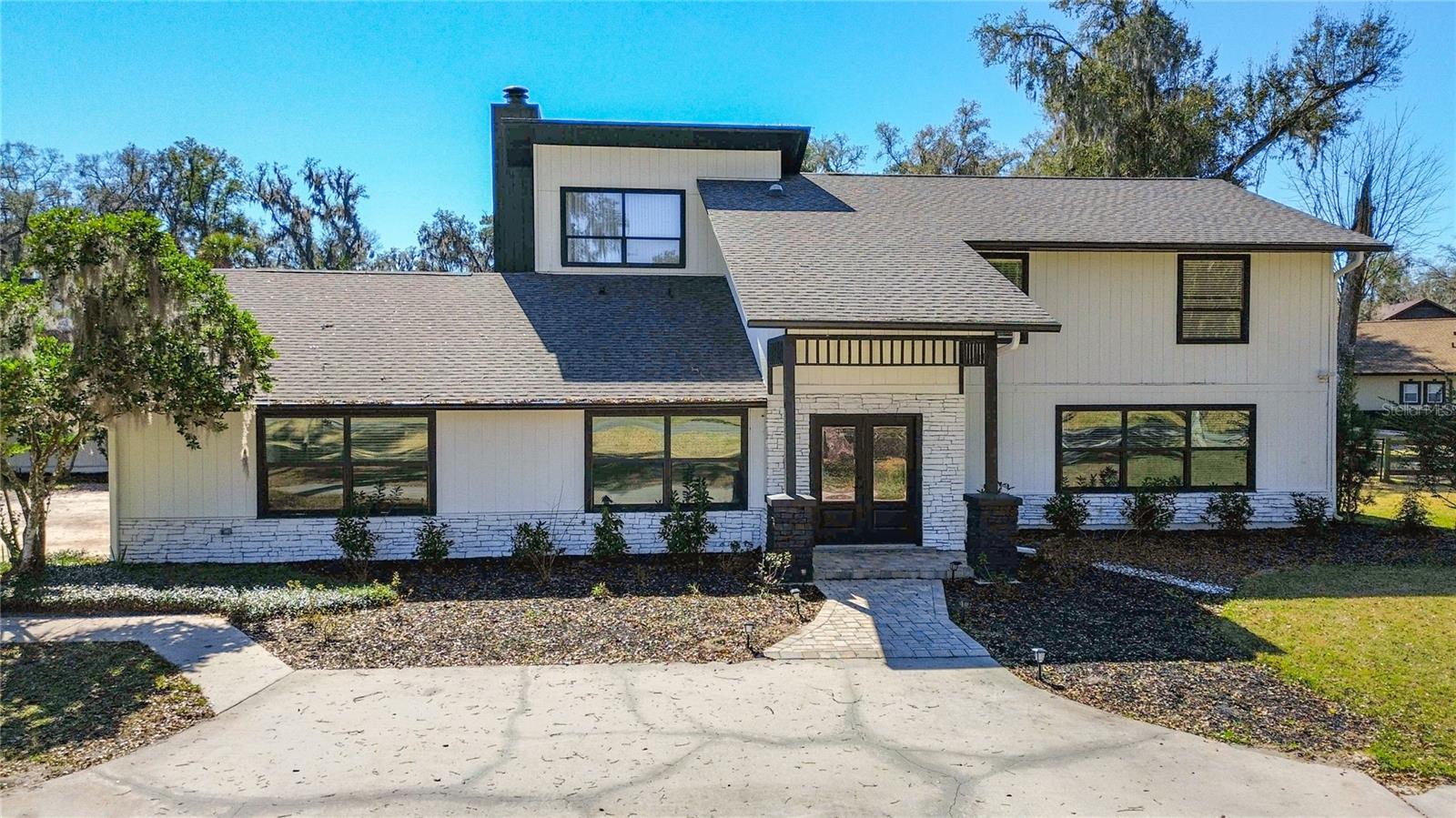 Welcome to a fully reimagined modern estate in one of Ocala’s most desirable settings. This two story pool home sits on a spacious and private lot surrounded by mature trees and open greens that create a peaceful atmosphere while keeping you close to everything. The property has been completely remodeled from top to bottom with quality finishes throughout.The interior features new flooring, fresh paint, updated lighting, new doors, and an open layout that connects multiple living areas. The kitchen has been redesigned with full height cabinetry, a large island, premium countertops, upgraded appliances, and clear views of the pool and backyard.The primary suite upstairs includes a private balcony overlooking the property. The downstairs suite is a true showpiece with a massive double walk in shower that features multiple body jets on each side for a spa level experience. All bathrooms have been updated with modern tile, new vanities, and clean fixtures.Major system upgrades add long term value including a new upstairs AC unit, a new irrigation system, a new water filtration system, a recently updated roof, and a serviced septic system. The pool has been completely resurfaced in Marcite and paired with a new pool pump for a crisp and long lasting finish.The outdoor space stands out with a large pool, spa, covered patio, fire pit pad, and a spacious yard ideal for gatherings or future additions. Mature landscaping frames the property and provides a private estate feel.The home is located in a gated community with security at the entrance along with tennis courts and a basketball court. The location is a major advantage and places you within minutes of all major shopping and restaurants. Paddock Mall is only two and a half miles away.