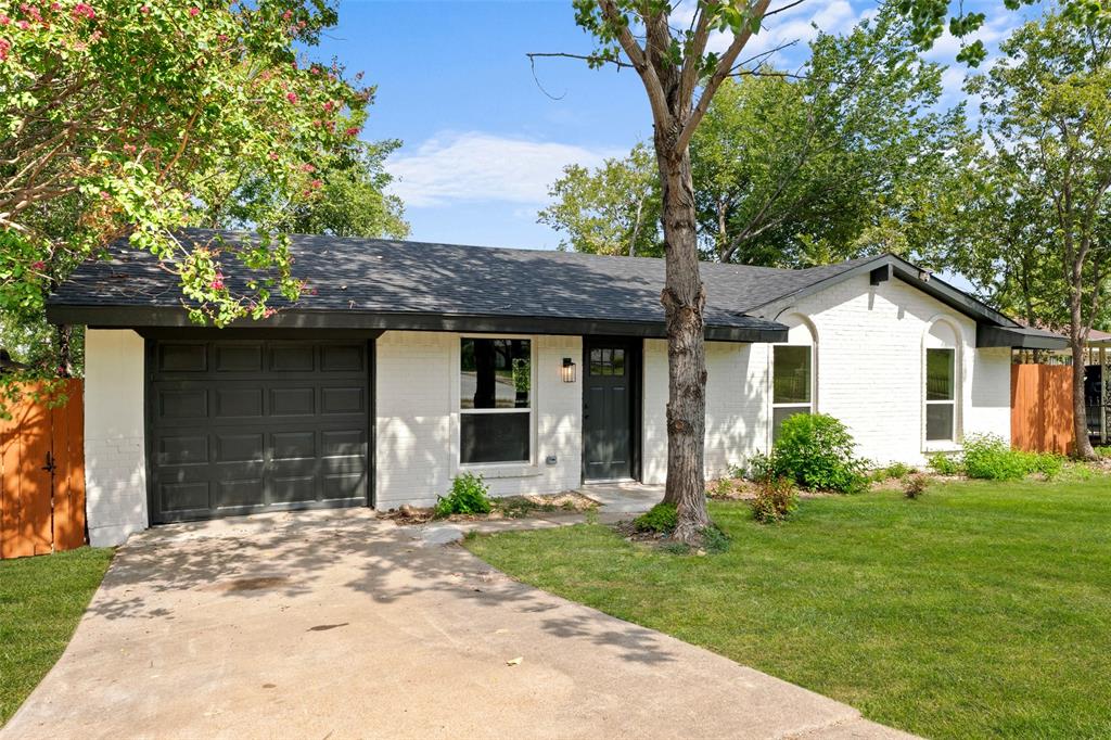 Ranch-style house with brick siding, a front lawn, concrete driveway, roof with shingles, and an attached garage