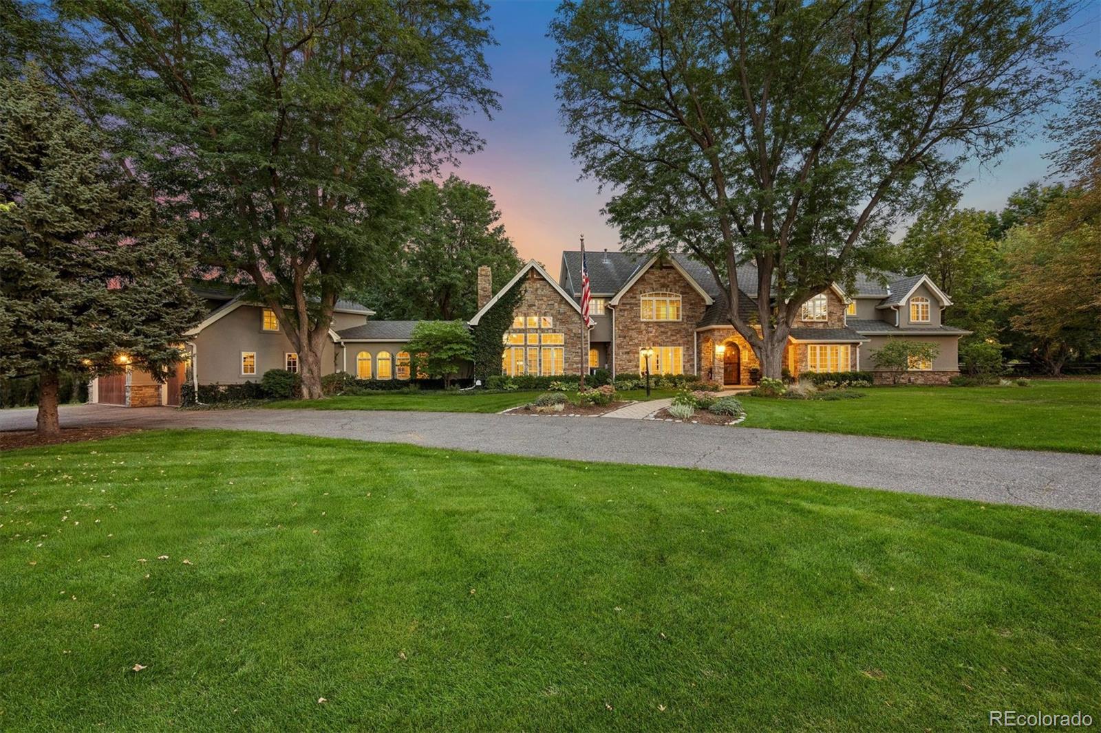 Set among mature trees in Old Cherry Hills, 5 Viking Drive is a six-bedroom residence defined by timeless architecture, beautifully scaled interiors and exceptional indoor-outdoor living. A circular drive introduces the stone façade, framed by ivy and established landscaping.Inside, detailed millwork, French doors and custom built-ins reflect the craftsmanship throughout. Formal living and dining rooms offer elegant spaces for entertaining, while multiple fireplaces bring warmth to the interiors. A richly paneled private office with custom cabinetry, wet bar and French doors opening outdoors creates a handsome retreat.The expansive kitchen features a substantial island with seating, Viking, Thermador and Sub-Zero appliances, a walk-in pantry and adjoining butler’s station. The kitchen opens to a casual dining area and vaulted family room with exposed beams, a stone fireplace, built-in cabinetry and window seating. A Dutch door extends the living areas to the covered patio and backyard.The upper level offers six bedrooms and a dedicated laundry room. The spacious primary suite features vaulted ceilings, a private balcony and dual custom walk-in closets. The primary bath includes heated floors, dual vanities, a soaking tub beneath skylights and an oversized steam shower. Four additional bedrooms feature en-suite baths and generous closet space. A separate sixth bedroom accessed from the rear staircase includes a three-quarter bath and custom built-ins, offering flexibility for guests, playroom or private workspace.The covered patio features a gas fireplace and built-in Viking outdoor kitchen for dining and entertaining throughout the seasons. Beyond, the fully fenced grounds offer mature landscaping, a putting green, in-ground trampoline, play area and vegetable garden. A three-car garage and abundant storage complete this thoughtfully designed Old Cherry Hills residence.