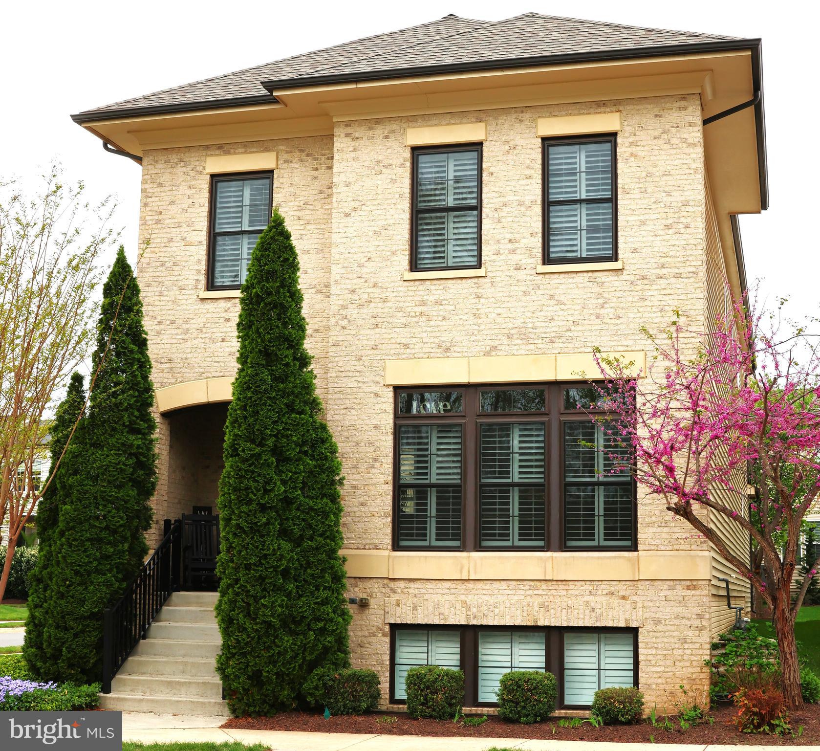 Welcome to 20405 Savin Hill, an extraordinary brick residence ideally situated on a corner lot adjacent to Central Park in the highly coveted One Loudoun community. Spanning three impeccably finished levels, this exceptional home combines timeless architecture, refined interiors, thoughtful custom enhancements, and exceptional attention to detail throughout.The main level immediately impresses with elegant plantation shutters, engineered hardwood flooring, sophisticated millwork, and an inviting foyer that introduces the home’s exceptional flow. A private front office with custom built ins provides a beautifully appointed setting for working from home or quiet study.At the center of the residence is an impressive chef’s kitchen designed to be both visually striking and highly functional, featuring custom cabinetry, granite countertops, stainless steel appliances, and a substantial center island. The kitchen opens seamlessly to an expansive dining area and a light filled family room highlighted by a contemporary fireplace. The adjacent deck extends the living space outdoors and provides an inviting setting for entertaining or enjoying the surrounding views.A thoughtfully designed mudroom provides direct access to the oversized rear load two car garage, adding both convenience and functionality to the main level.The upper level offers four bedrooms and three full baths, including a luxurious owner’s suite with engineered hardwood flooring, a custom designed walk in closet, and a spa inspired bath. A private three season sunroom extends from the owner’s suite, offering a peaceful retreat overlooking the surrounding grounds. The upper level loft, complete with custom built ins, provides an elegant and versatile space for a study area, reading room, or additional lounge.The finished lower level offers an exceptional extension of the home’s living space with a spacious recreation room and bar, abundant natural light, a legal fifth bedroom or exercise room, and an additional full bath. Nine foot ceilings on all three levels further enhance the home’s sense of volume and grandeur.Additional improvements include updated lighting, three solar tubes, a newer roof, newer water heater, and new sump pump. Positioned directly adjacent to Central Park, this exceptional residence places you moments from the acclaimed restaurants, boutique shopping, entertainment, and everyday conveniences of One Loudoun, while Dulles International Airport is approximately 10 minutes away.A rare opportunity to own a truly distinctive residence in one of Loudoun County’s most sought after communities. Experience the exceptional setting, remarkable scale, and refined details of 20405 Savin Hill firsthand.