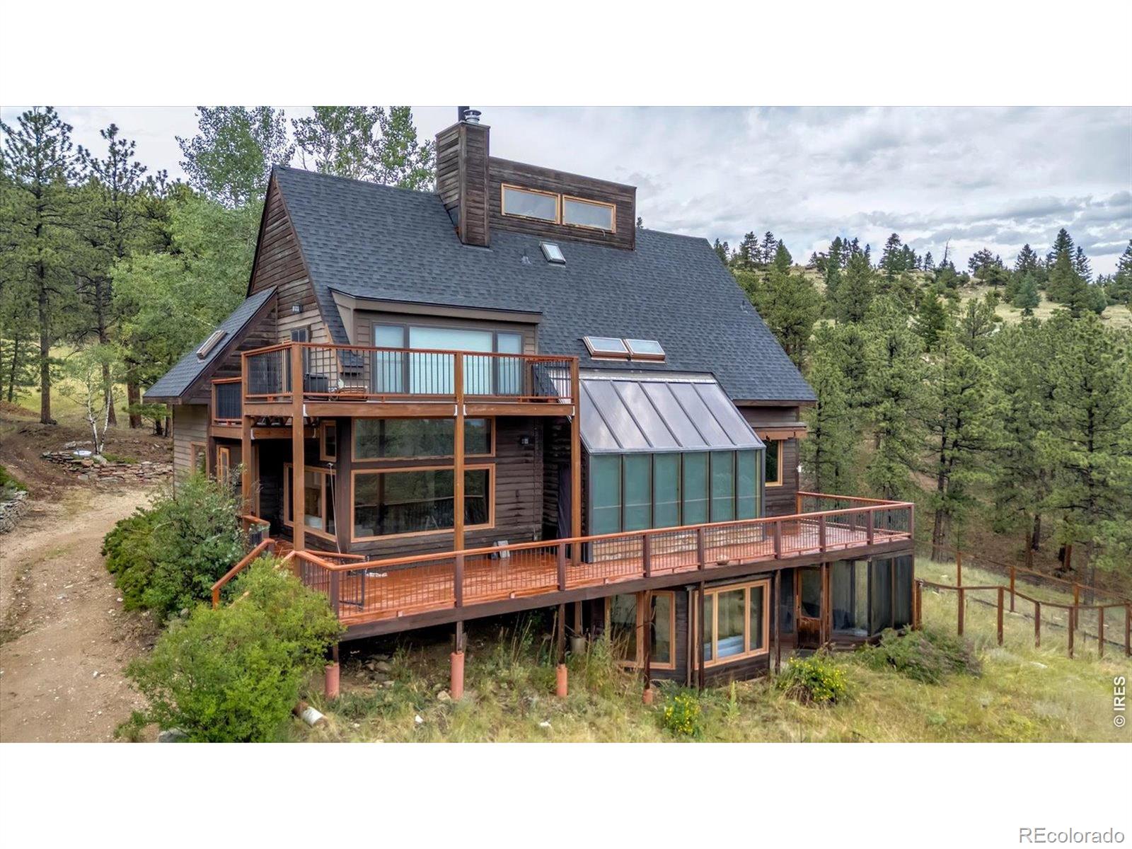 A rare opportunity to own a private mountain retreat on 35 acres, just 15 minutes above Boulder. The inviting living room, anchored by a cozy fireplace, flows into a spacious kitchen and dining area designed for gathering with family and friends. Expansive windows throughout the home frame the natural beauty of the surrounding landscape, filling each room with abundant light and tranquil views. The recently remodeled primary suite offers a peaceful sanctuary, complete with a private loft ideal for yoga or meditation, a balcony and a generous walk-in closet. The bright, walkout lower level features a spacious family room, an additional bedroom, and a full bathroom. Above the garage, a charming studio provides exceptional flexibility, featuring a fourth bedroom, a three-quarter bath, and a comfortable sitting area-ideal for guests. Unwind on the sun-drenched decks or step directly from your property onto the trails of Betasso Preserve for endless hiking and outdoor recreation. The old barn accommodates two horses with ample hay storage, adding to the property's exceptional versatility. This is a truly one-of-a-kind property that must be experienced in person.