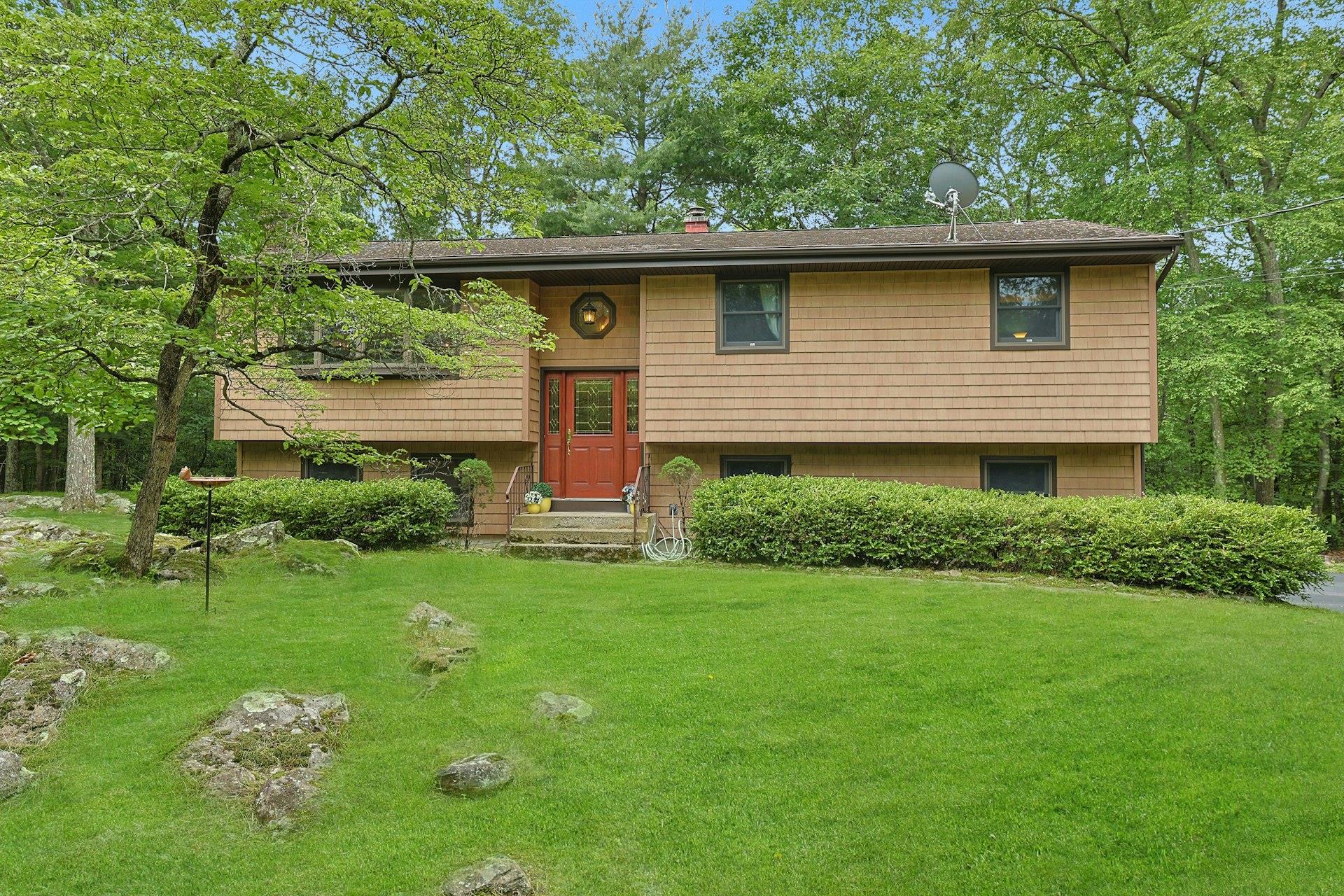 SERENE retreat in beautiful North Salem with Lake Hawthorne privileges! Tucked in back of 2 enchanting acres of grassy lawns, gentle slopes, and woods for privacy, is a 3 bedroom, 2 bath raised ranch that is easy to care for and easy to love. The main level offers hardwood floors and natural light, with garden views from the living room picture window. The dining room opens to the back deck and the eat in kitchen, making entertaining a breeze. Speaking of kitchen, who can resist a built-in breakfast nook, thoughtfully designed cabinets & quartz counters? Down the hall are 3 restful bedrooms and a full bathroom. Downstairs, is a huge family room (shown here with a recreation space with wood burning fireplace plus room for a home office for 4). A full bathroom, laundry room, and entry to the 2 car garage round out the lower level. There's plenty of space in the driveway for the guests you will be inviting over to enjoy frisbee or volleyball in the side yard, or to canoe on the lake. Lake Hawthorne Homeowners Association ($300/yr) gives access to swimming, picnic area, row boat/canoe privileges. Just a stone's throw to I-684, Caramoor Center for Music & Art, and restaurants & shops in nearby Katonah, Bedford, Ridgefield and Mt Kisco. Must see in person to experience the tranquility. You won't want to leave!