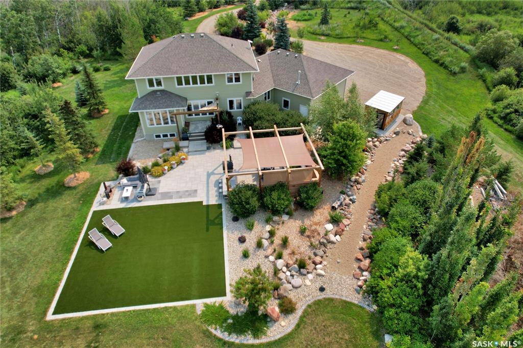 Welcome the perfect Saskatchewan paradise — an extraordinary 2-storey Westridge built home set on just over 5 beautifully landscaped acres, only 12 minutes from Saskatoon. This property offers the perfect blend of luxury, space, and outdoor lifestyle, with every detail thoughtfully designed for comfort and style. You'll be welcomed by the gorgeous East facing porch perfect for a morning coffee. Step through the grand front entrance into a bright, open interior filled with natural light. The open floor concept allows for the perfect family or entertaining setting. The kitchen's oversized island and gorgeous quartz countertop with a corner pantry make it the perfect space to cook and connect. The main floor features an office, large mudroom with laundry and a stunning primary bedroom retreat, complete with a spa-like ensuite and a spacious walk-in closet. Upstairs, you'll find three more bedrooms plus a large bonus room, offering plenty of space for family, guests and everything in between. Outside, the exquisite yard is an entertainer's paradise. Enjoy summer evenings with your very own outdoor kitchen, wood-fired pizza oven, and above-ground pool, all set against the backdrop of breathtaking Saskatchewan sunsets. A heated triple attached garage provides ample space for vehicles, toys, and tools, making this property as functional as it is beautiful.