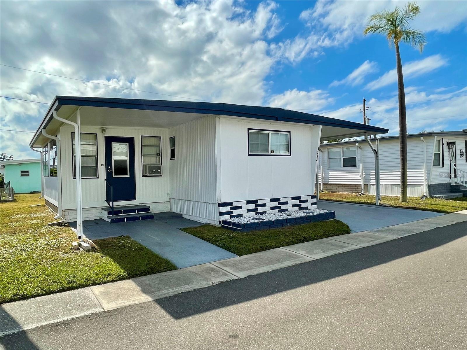 VOTED ONE OF THE TOP 5 RETIREMENT COMMUNITIES IN 2025!! 2 bed, 1.5 bath, Florida room home in a well desired 55+ park. This home comes TURNKEY, MOVE RIGHT IN... SHARE is included in list price (valued at $55,000); Home has updated touches throughout the home, #1 is the kitchen featuring ample amount of warm wood cabinetry, countertop and backsplash... newer lighted fans in both bedrooms... some updated light fixtures... water heater 2023... Roof is coated every 2/3 years... laminate flooring throughout, NO CARPET! Much sitting/entertaining area under the covered front patio, side patio surrounded by a privacy fence AND a sitting area added by the seller for some great sunning on the side of the privacy patio. This park is in close proximity to the beaches, airports, I – 275, churches, restaurants, all kinds of shopping, etc.… very inexpensive living at ONLY... $210 per month which includes all the amenities one could want; WATER, SEWER, and TRASH, owned clubhouse, escrows are fully funded, beautiful heated pool and spa, fitness center, library, shuffleboard, billiard table, and a small lake at the back of the park, laundry room, and your very own private entrance to the super Walmart… on foot, bicycle or golf cart… Etc., etc. GOLF CART included!