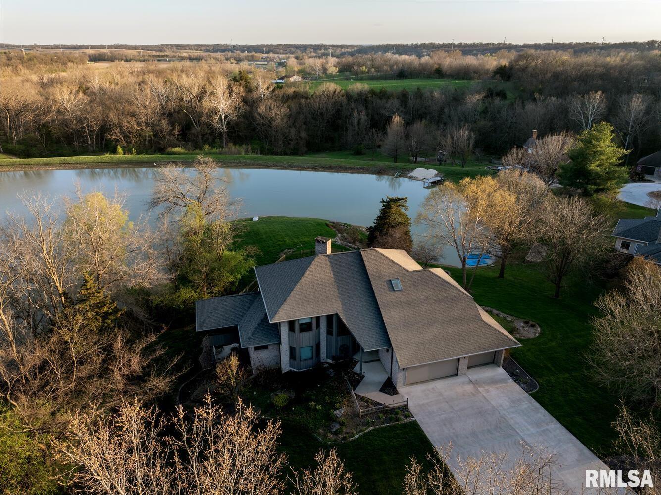 Experience lakefront living with exceptional light, volume and views in this thoughtfully designed 5-6 bedroom, 4 bath, two-story home. A wall of dramatic two-story windows floods the living room with natural light and frames water and woods views beyond the private deck. The living area centers on a stone fireplace and opens to comfortable seating areas table that highlights the expansive sightlines. The primary suite offers privacy and an en-suite bath featuring a corner soaking tub, dual vanities and generous closet/storage space. Additional rooms include a cozy screened porch/sunroom, an main-floor bedroom, and flexible bonus spaces ideal for an office or media room. A three-car garage and ample storage complete the practical side of this home. Outside, enjoy tiered outdoor living — upper deck for dining, covered lower patio for lounging, and a fenced yard with direct lake access. Mature trees and manicured lawns provide a private setting for entertaining, boating or quiet mornings by the water. Well-maintained and move-in ready, this property blends indoor/outdoor living with classic comfort and thoughtful layout.