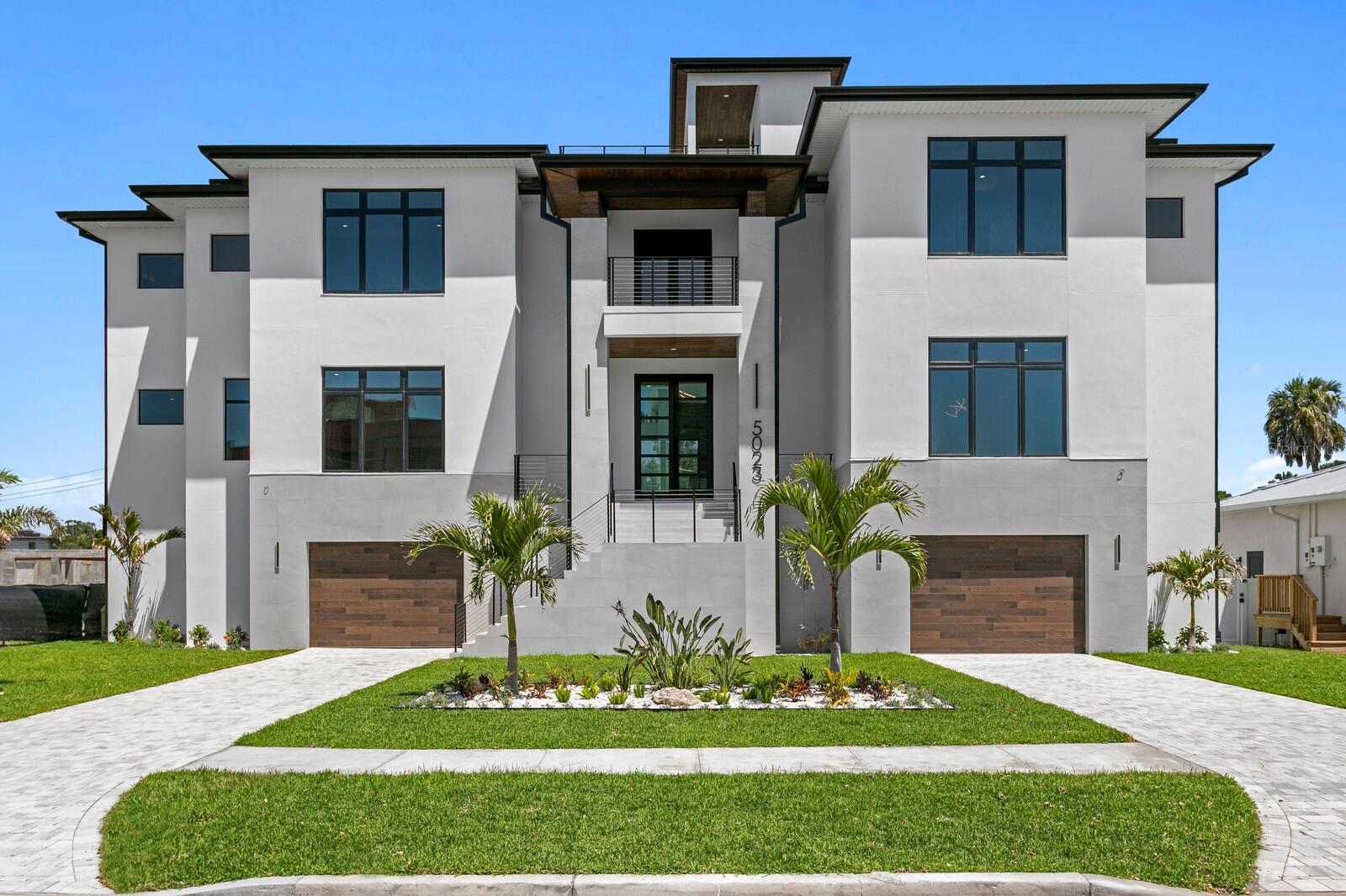 Brand-new construction (Completed) with modern coastal design, open-water views from a rooftop deck, 8-car garage capacity, and elevated living areas define this new waterfront residence thoughtfully designed and built in the new community of Madsen Isles in South Tampa. Designed for Florida living, the home offers generous indoor-outdoor spaces, quality construction details, masonry concrete block construction, impact-rated windows and doors, and a 4-story elevator. Exceptional living spaces are anchored by an impressive light-filled great room with a 24-foot tiled fireplace wall and 360-degree floating custom fireplace, brushed white oak wood floors, an entertaining bar, and statement lighting. A sleek European-inspired chef’s kitchen features dual quartz islands with waterfall edges, generous seating, Sub-Zero and Wolf appliances, and open connection to the breakfast area and great room, with access to a covered terrace and outdoor kitchen with gas grill, stainless steel sink, mini fridge, and custom countertop. Additional features include a 3-row movie theater with 120” screen and Dolby Atmos 7.1 pre-wire, wine room, lounge, office, powder bath, and five bedrooms with five full baths and one-half bath. A floating staircase leads to the upper living level, where the primary retreat includes a 650-square-foot primary bedroom with private balcony, his-and-her walk-in closets, and a spa-inspired bath with a vessel tub, makeup vanity, and dual rainfall shower heads. Outdoors, enjoy a waterfront pool with sun decks, floating spa, fireplace, covered entertaining areas, tongue-and-groove terrace ceilings, and an outdoor floating staircase connecting the pool area to the living level. The rooftop deck extends the outdoor living experience with open-water views, while the garage level provides rare 8-car capacity. Madsen Isles is an exclusive South Tampa waterfront enclave planned for eight homesites, including six waterfront properties and two off-water properties, with brick paver roadways, underground utilities, and a setting designed to offer a refined residential experience near downtown Tampa, Tampa International Airport, dining, shopping, recreation, sports venues, and area beaches.