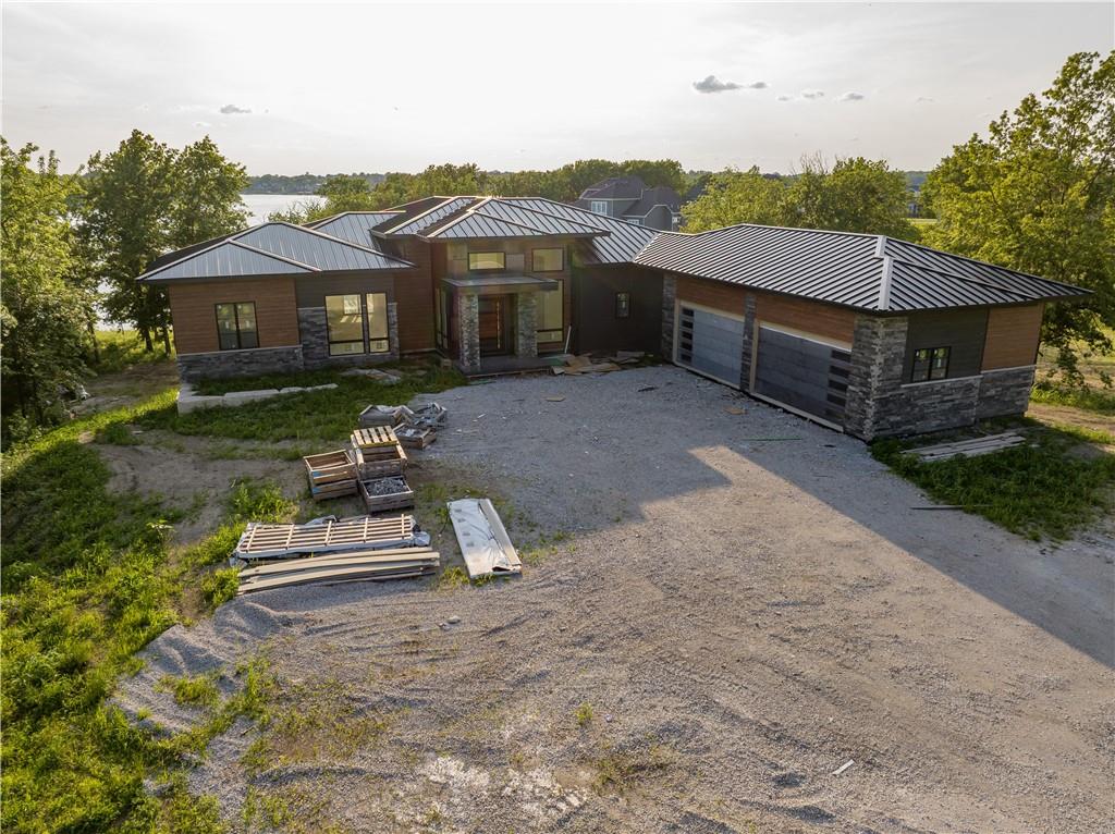 Experience refined lakefront living on the private waters of Lake Winnebago in this exceptional custom modern craftsman by Walker Custom Homes—proudly prepared for Kansas City’s 2026 Artisan Tour. Perfectly positioned on a premier lot with a gentle slope to the water’s edge, this residence blends architectural elegance with resort-style amenities.Designed for both everyday comfort and elevated entertaining, the home features 4 bedrooms plus an expansive bunk room, including two luxurious main-level suites and additional bedrooms in the walkout lower level. Thoughtfully curated spaces include a private pocket office, full prep kitchens on both levels, a stunning wine cellar, and a showpiece wet bar.The lower level is truly next-level, highlighted by an incredible theater room, dedicated workout space, and seamless access to outdoor living. Step outside to your private oasis featuring a custom pool and spa, along with multiple covered decks designed to capture breathtaking lake views.Car enthusiasts and hobbyists will appreciate the suspended slab 4-car garage, complemented by a rare 5th rear garage door—perfect for lake gear and easy backyard access. Built on a 12 ft foundation, this home offers both scale and structural distinction rarely found in lakefront construction.No detail has been overlooked—finishes are truly over-the-top, with the opportunity to personalize a few selections and make this home uniquely yours.Bulkhead and dock anchors are already in place, making it easy to complete your ideal lake lifestyle. This is a rare opportunity to own a fully customized luxury retreat in one of the area’s most sought-after communities.