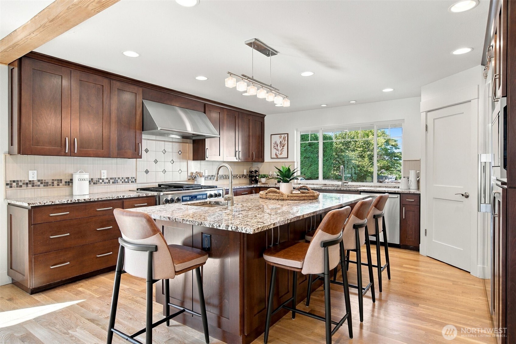 The chef's kitchen pairs rich wood cabinetry with a granite island, bar seating and a professional-grade range.