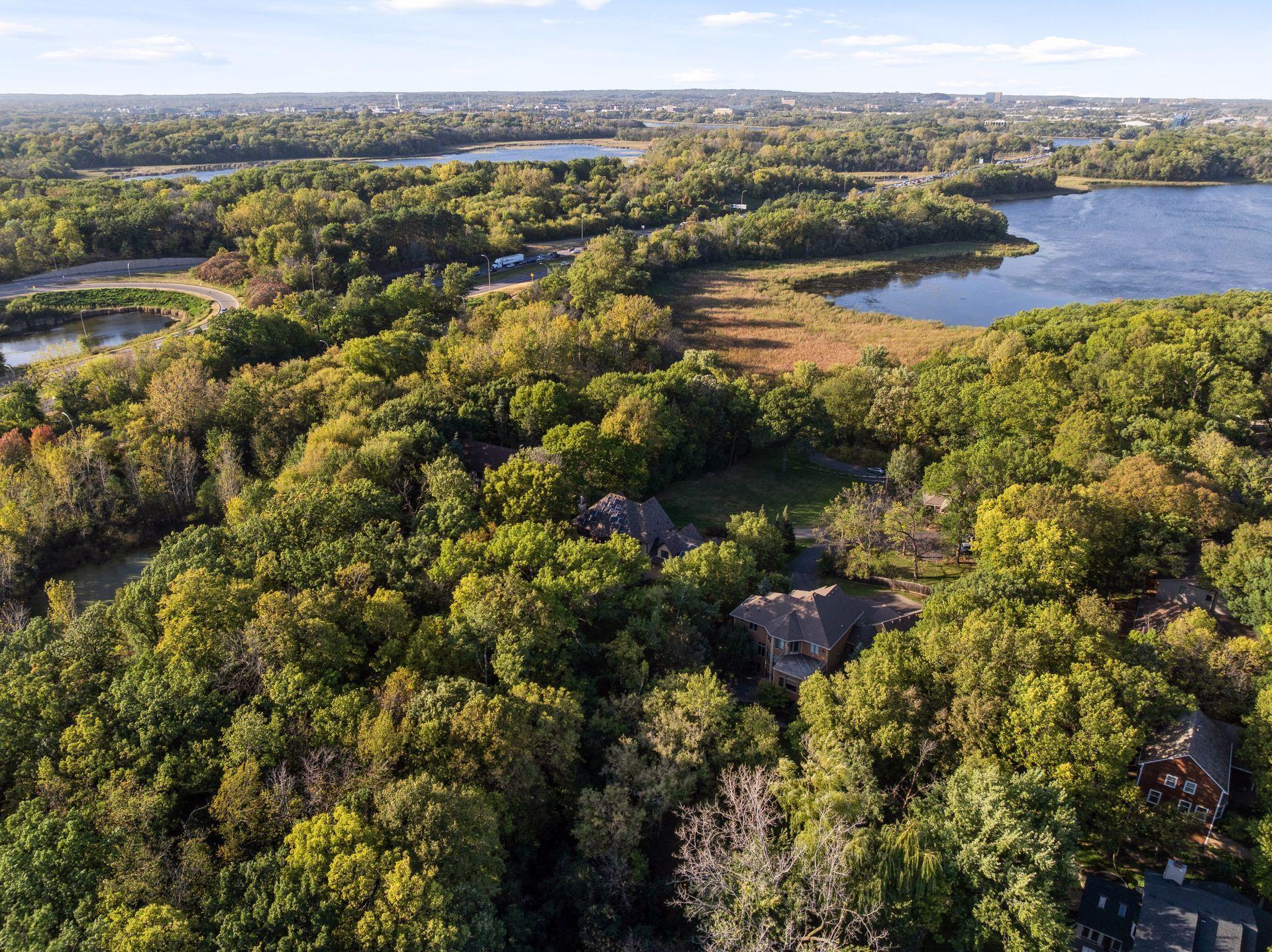Experience the perfect harmony of elegance, innovation, and nature in this secluded 1.5-acre wooded estate nestled between Anderson Lake, Bush Lake and the 1,100-acre Hyland Lake Park Reserve. Crafted with Venetian plaster walls, Bolivian rosewood floors, and freshly painted interiors, every space radiates timeless sophistication. The chef’s kitchen, equipped with Wolf and Sub-Zero appliances, a massive honed granite center island, and a butler’s pantry, sets the stage for inspired entertaining. A main-floor office provides a refined workspace, while the lower level offers a home theater, wet bar, fireplace, and guest suite with private bath and walkout to a flagstone patio. Enjoy effortless indoor-outdoor living with a summer screen porch and expansive deck overlooking a gated, pet-friendly backyard with abundant wildlife. Each upper-level bedroom features its own bath, and the primary suite boasts a spa-inspired ensuite with heated floors. Exquisite smart home with solar panels, EV charging, and proximity to MSP International Airport, this  prestigious West Bloomington estate blends luxury, privacy, and convenience.