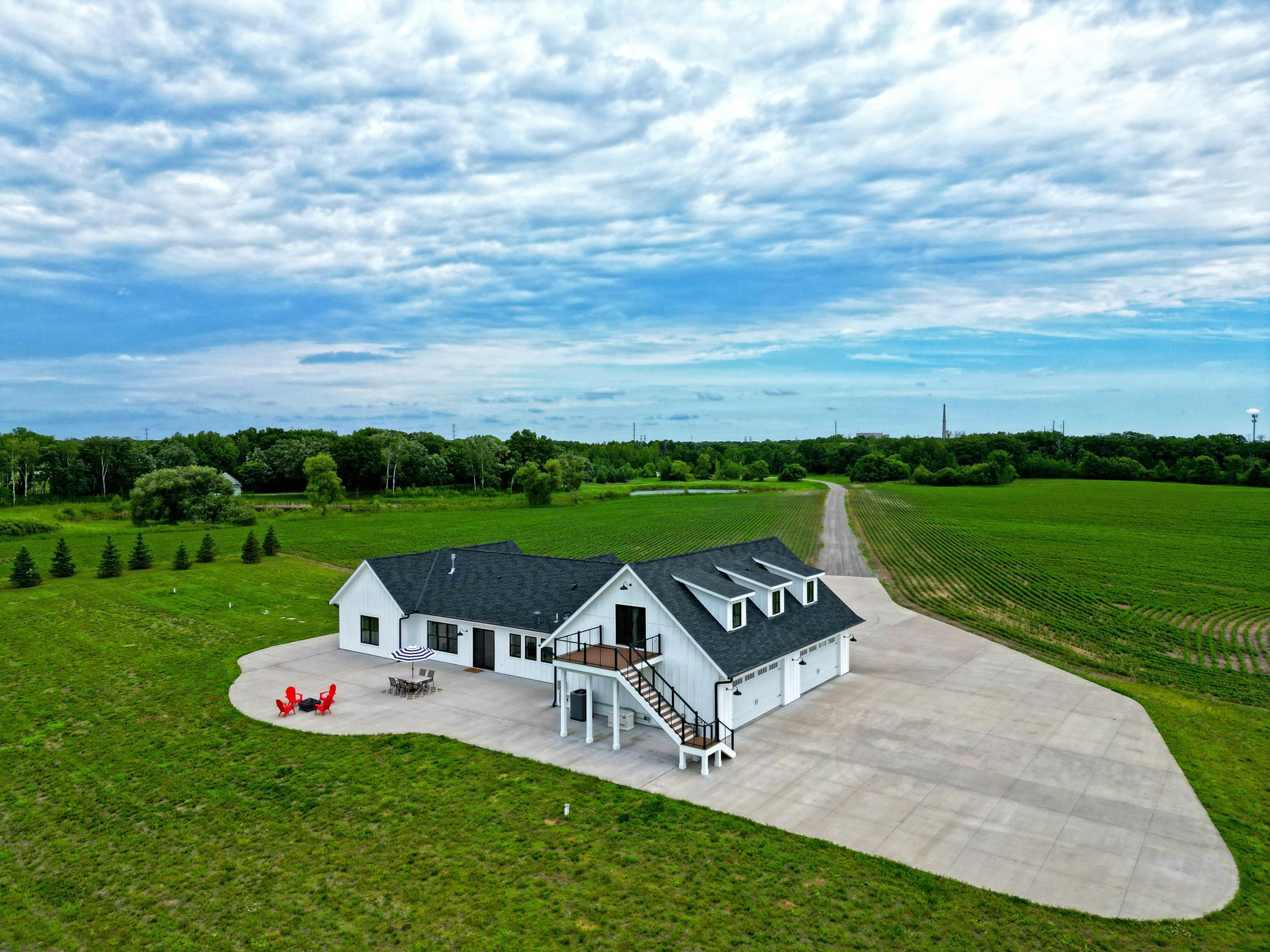Set on 85 picturesque acres with approximately 35 tillable acres, this exceptional country estate offers privacy, space, and breathtaking views in every direction. The beautifully designed home features a 4-car garage and an impressive gourmet kitchen that flows into the living room, highlighted by custom reclaimed wood and beadboard ceiling accents. A wall of glass across the main living area brings the outdoors in and showcases sweeping countryside views. The main level offers a spacious primary suite complete with a luxurious bath and soaking tub, along with a second bedroom, office, laundry room, and half bath. Upstairs, you'll find a large family room, third bedroom, and full bath, ideal for guests or additional living space. Step outside to expansive patios and entertaining areas designed for gathering with family and friends while enjoying the peaceful rural setting. Adding to the property's appeal is a charming bunkhouse overlooking the pond in a secluded location. Already gutted and ready for your finishing touches, it presents endless possibilities as a guest retreat, studio, or recreational space. A rare opportunity to own an incredible acreage property that combines modern comfort, productive farmland, scenic ponds, and the tranquility of country living.