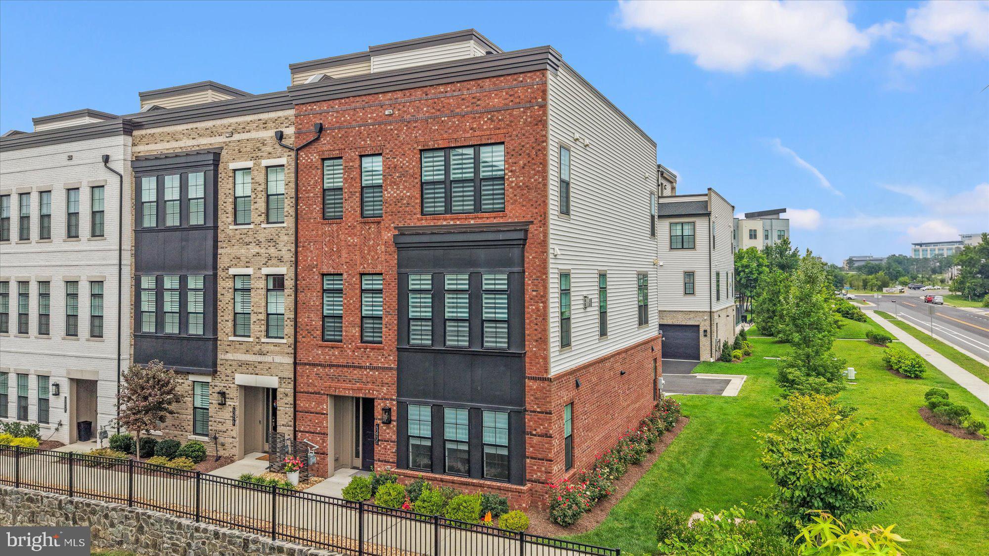 43931 Norman News Terrace is a stunning end unit townhome with elevator access to all four levels in the popular Regency at Belmont Chase 55+ community. Featuring over 3250 square foot of exceptional living space with an open and sophisticated floor plan, elevated ceilings, abundant natural light and a spacious rooftop terrace. This beautiful home was recently built to the highest standard with over $250,000 in builder upgrades and is better than new with an additional $30,000+ in owner investments and thoughtful designer touches.  The gracious foyer leads to the entry level with a large bedroom or office with a full bath and garage access. Wide plank oak hardwood flooring and an oak staircase adorn the entry and main level. Upstairs is the living room anchored by a gas fireplace, dining room that can accommodate large gatherings, a gourmet kitchen with oversized center island, high end cabinets, quartz countertops and backsplash, Sub Zero refrigerator, a six burner gas cooktop and a full pantry with shelving and wine cooler. The bedroom level contains a lovely owner’s suite with a large walk in closet and bath with double vanity, Italian tile and high end finishes. This level also boasts a spacious guest bedroom with a second walk in closet, full bath and a laundry room with an upgraded LG front load W/D, sink and wood cabinetry. The final level contains a wrap-around rooftop terrace with LPV flooring, a gas fireplace and retractable awning. Enjoy entertaining, BBQ and peaceful views from over 800 square foot of outdoor living. Extensive audio visual features include a surround sound system in the living room, outdoor music listening area on the roof deck and Eros distributed Wi-Fi with units on each floor. Additional owner upgrades include designer wall paper and paint, Hunter Douglas electric window shades, upgraded lighting, EV 2 car charger system, front and side yard irrigation system and garage and closet organization systems. Belmont Chase is a well-managed and active community offering neighbor social gatherings, a community gazebo and access to the Belmont Country Club with pool, tennis, pickleball, fitness center and dining. Additional golf privileges available if desired. Walkable to shopping, dining and Whole Foods and easy access to Dulles Airport, INOVA hospital and the metro. Move right in to this singular residence and community, an incomparable Ashburn value and opportunity.