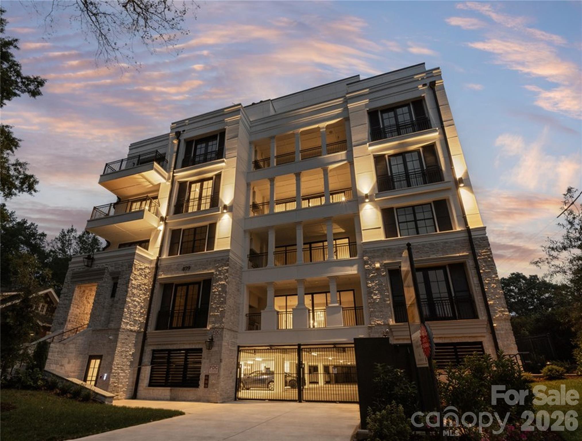 An extraordinary next chapter deserves an equally extraordinary address. Double entry doors open to a spacious foyer, with European white oak floors connecting the living, dining, and sitting areas. Soaring 18-foot ceilings, a statement double-sided fireplace, and an expansive east-facing terrace distinguish this 4,518-square-foot penthouse at Four09 Queens in Myers Park. One of just two top-floor residences in this boutique 17-home building, Unit 503 offers four en-suite bedrooms, a dedicated office, and exceptional single-level living. Everleigh quartz and custom white-oak millwork frame the fireplace, while double sliding doors extend all three gathering spaces onto the terrace with a built-in grill. A glass-enclosed wine room and wet bar with dual Sub-Zero wine refrigerators create a striking entertaining space.The kitchen features waterfall-edge quartz countertops, a full-height backsplash, a quartz-clad hood, a 48-inch Wolf eight-burner range with double ovens, cabinet panel Sub-Zero refrigeration, microwave and warming drawers, an ice maker, and an adjoining pantry. Under-cabinet and floor-level lighting highlight the cabinetry and finishes.The primary suite includes a customized walk-in closet with glass-front cabinetry, drawers, and quartz countertops. Its spacious bath offers dual vanities, a freestanding soaking tub, and an oversized shower with multiple shower fixtures plus a rain head and a bench. Three additional bedroom suites, an office with illuminated built-ins, and a laundry room with two full-size stacked washer/dryer sets complete the residence.The only unit with three assigned garage spaces, and the largest of only two storage units in the building access to a private fitness center, a club room with wine area and fireplace, guest lobby, covered outdoor lounge with TV, and a fenced dog area. Completed in 2025, this penthouse combines the scale of a custom home with the convenience of condominium living in Myers Park near Uptown and SouthPark.