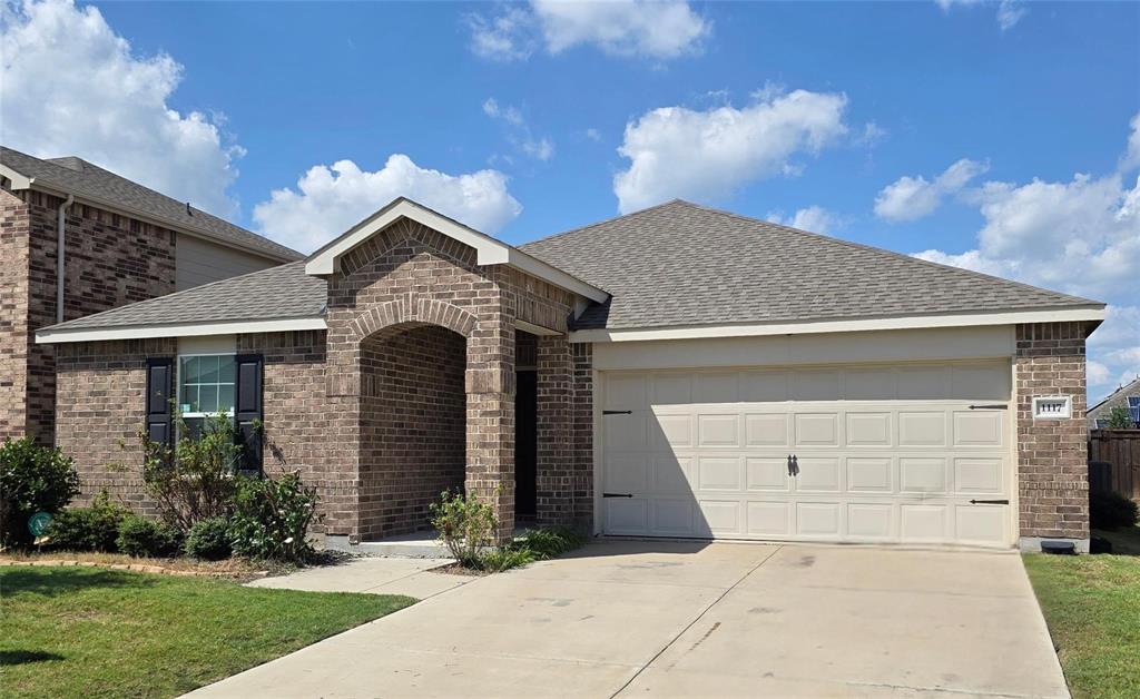 Brick exterior residence featuring an arched entry, two-car garage with decorative hardware, and dark window shutters
