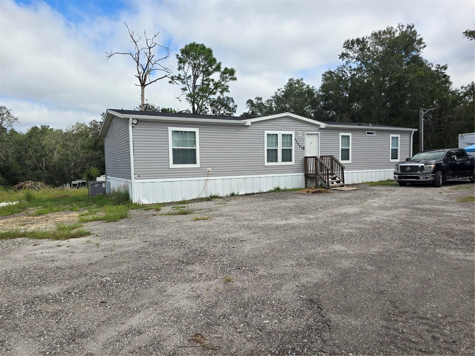 MANUFACTURED HOME ON 4.78 ACRES IN PASCO COUNTY! Discover the perfect blend of space, comfort, and convenience in this like-new 4-bedroom, 2-bathroom manufactured home situated  in Pasco County, just minutes from the Suncoast Parkway. Offering plenty of room to spread out, this property is ideal for those looking for privacy, storage, and modern living without sacrificing convenience. Step inside and you'll immediately notice the abundance of natural light, thanks to the home's many double-pane windows that brighten the living spaces and create a warm, inviting atmosphere. The spacious open-concept kitchen is designed for entertaining, featuring a huge center island, wine bar, abundant cabinetry, and a cleverly hidden walk-in pantry that provides incredible storage while keeping everything tucked away. The desirable split-bedroom floor plan offers privacy, with the spacious primary suite separated from the secondary bedrooms. The primary bathroom is a true retreat, featuring a huge soaking tub, walk-in shower, tons of cabinetry, and plenty of counter space. Outside, the almost 5-acre lot gives you room to spread out and enjoy the space, parking your boat, RV or storage sheds.