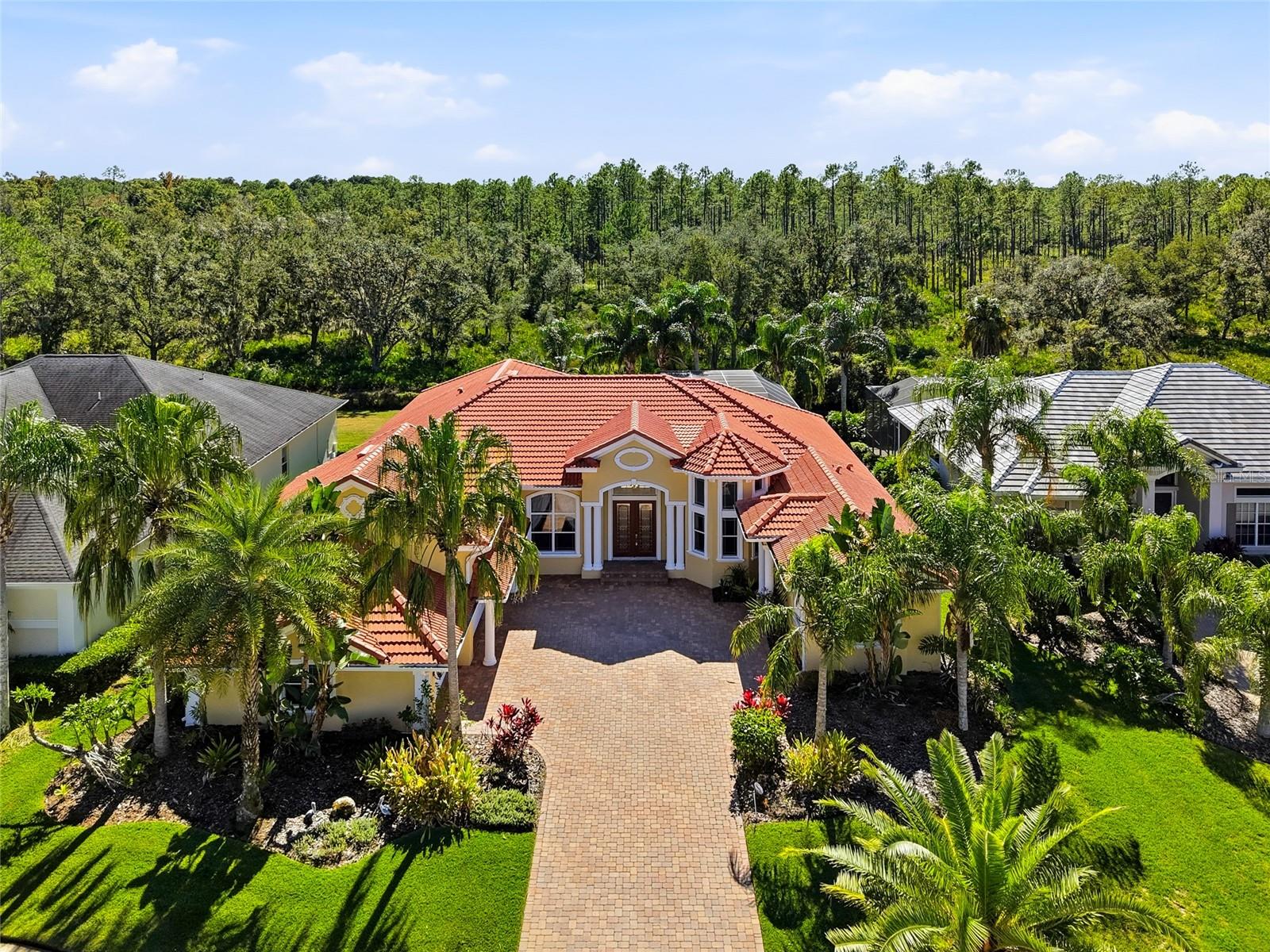 One or more photo(s) has been virtually staged. Distinction with Heart and Craftsmanship. Some homes catch your eye. This one captures your heart.

Set behind the gates of Cory Lake Isles, this true custom-built house blends timeless elegance with everyday comfort, offering craftsmanship, warmth, and modern sophistication in every detail.

Walk through the grand double doors and you’re immediately surrounded by quality. Hardwood and travertine floors, architectural ceilings, and custom millwork create a rich yet welcoming atmosphere. The home flows naturally from its formal gathering areas into open, relaxed living spaces filled with natural light and scenic views.

At the center of it all is a chef’s kitchen designed for connection and convenience. Solid wood cabinetry, thick granite countertops, a built-in refrigerator, and an oversized island make this the perfect place to cook, host, or simply enjoy family time. The adjoining family room, with custom built-ins and coffered ceilings, overlooks the lanai and pool, blending indoor and outdoor living effortlessly.

Open the glass sliders and step into your own private retreat. The screened lanai, heated pool, and spa sit against a peaceful conservation backdrop overlooking Flatwoods Preserve, creating a setting that’s equal parts relaxing and inspiring.

The primary suite offers true tranquility with a spa-inspired bath, jetted soaking tub, walk-in shower, and double custom closets designed with care.

A private in-law suite brings both flexibility and sophistication with its own entrance, large living area, and full bath, ideal for guests, extended family, or a quiet home office.

Every corner of this home reflects craftsmanship and comfort and there are way too many upgrades to list. Custom ceilings, crown molding, solid doors, whole-home audio, video, Wi-Fi system, and smart wiring add both beauty and function. The granite-finished laundry room with full cabinetry and the three-car side-entry garage complete the thoughtful design.

Living in Cory Lake Isles means enjoying a true resort lifestyle, with a lakefront clubhouse, fitness center, tennis courts, walking paths, and access to the 165-acre ski lake right at your doorstep.

Elegant yet inviting. Sophisticated yet warm, this home is more than a luxury home…it’s a place designed for connection, comfort, and lasting memories.