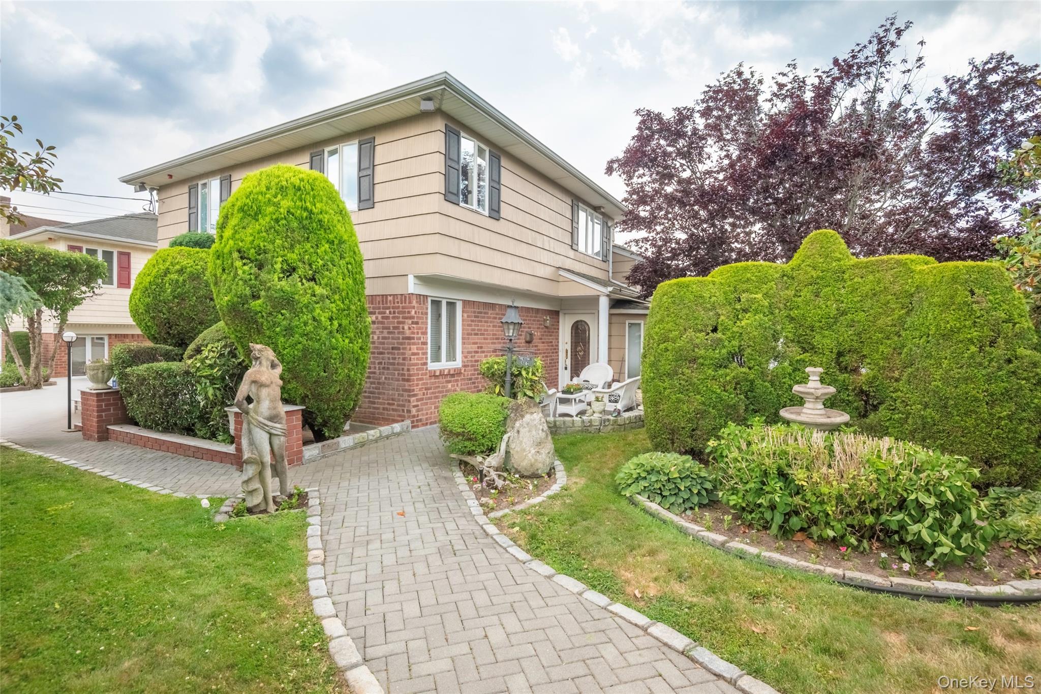 Welcome to this one-of-a-kind custom-designed residence in the prestigious Douglaston Park neighborhood. Showcasing luxurious inspired interiors and exceptional craftsmanship throughout, this remarkable stone home offers a unique blend of elegance, comfort, and functionality.This spacious multi level home is designed for both everyday living and entertaining. The inviting four-season sunroom and expansive balcony overlook the stunning heated in-ground pool, creating the perfect setting for relaxation and gatherings. The charming exterior features a beautiful combination of brick, cedar, and stucco, complemented by professionally landscaped grounds, an in-ground sprinkler system, and a security alarm system.Inside, custom teak flooring flows through the living room, dining room, and sunroom, while California-style ceilings, stone accents, and mirrored details add sophistication and character throughout the home. The renovated kitchen is equipped with a Jet Air cooktop and quality finishes. The spacious living room is highlighted by a cozy wood-burning fireplace, creating a warm and inviting atmosphere. It has 4 skylights.Step outside to your private backyard oasis featuring a 15' x 27' heated in-ground swimming pool, hot tub, and expansive patio area perfect for outdoor entertaining. The property spans two lots—Lot 98 (approximately 5,248 sq. ft.) and Lot 99 (approximately 2,300 sq. ft.)—offering exceptional outdoor space and privacy.Ideally located less than one mile from the Long Island Rail Road, providing a convenient 25-minute commute to Manhattan. Just two blocks from Northern Boulevard with access to local and express bus service. Close to shopping, schools, parks, and houses of worship. A truly special property with countless custom features—this is a must-see home!!