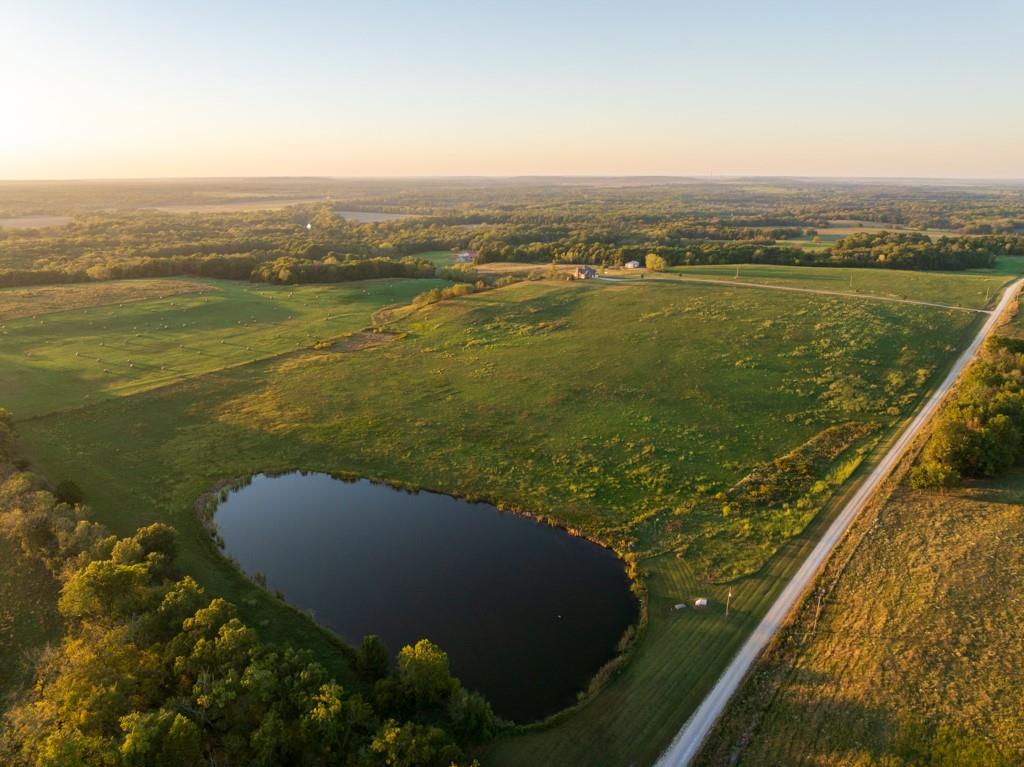 Make your dreams of living in the country a reality with this 71.6 +/- acre property that looks like a setting from a magazine. You will fall in love with the 1,000+ foot driveway access to the house that sits perfectly overlooking the property. Enjoy the sunrise and sunset views that literally go on for miles. The gently rolling land mainly consists of amazing pasture ground along with a 5 +/- acre patch of timber. It gets even better with a 2.5 +/- acre spring fed pond that is loaded with fish! The land offers it all and the real possibility of making it your very own country homestead. The 5 bedroom, 4.5 bathroom house was built in 2005 and offers plenty of space for the family and entertainment. It’s a must see! The main level features a living room with a fireplace, vaulted ceilings, formal dining room, oversized eat-in kitchen, and a master bedroom suite with picturesque countryside views. The upstairs includes 4 spacious bedrooms, 2 bathrooms, and an additional large play or storage room. The full walkout basement offers plenty of storage space and is currently framed as a separate studio apartment style living quarters for guests or in-laws. Another awesome feature is the oversized 5 car garage offering plenty of room for vehicles, gear, or a workshop. Don’t forget about the incredible deck off the main level with amazing scenic views.  Another bonus is the 30’x50’ outbuilding that will come in handy for storing farm equipment and other fun toys. This property checks all the boxes!