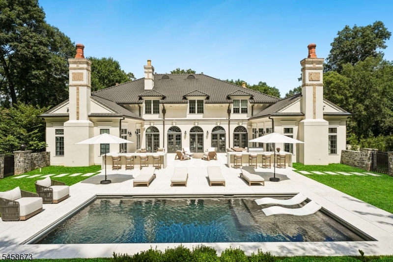 An extraordinary private estate where timeless architecture, uncompromising craftsmanship & resort-style living converge.Set at the end of a winding private drive on 3.48 acres of lush gardens & mature trees,this magnificent residence is a world unto itself.A grand 2-story foyer with coffered ceilings & sweeping curved staircase introduces interiors of exceptional scale. The formal DR features a dramatic glass-enclosed wine wall,while the richly paneled library offers a fireplace & wet bar.The breathtaking 2-story great rm centers around a fully equipped custom bar.The chef's kitchen is exceptional,appointed with custom white oak inset cabinetry,stone surfaces,herringbone hardwood floors, La Cornue range,True refrigeration, butler's pantry & breakfast bar, flowing into the elegant coffered family room. The 1st-floor primary suite is a private sanctuary with sitting room, coffee bar, luxurious dressing room & spectacular 2-story closet.The spa-inspired bath features oversized tile,soaking tub,European-style glass shower,floating dual vanities,makeup station, heated floors & private WC. Three ensuite bedrooms complete the upper level, plus a private guest apartment with LR, kit & full bath. The finished lower level rivals a private club with play, media & game rooms, gym, massage room, sauna & steam room. The newly completed yard is a private resort with checkerboard stone terrace,outdoor kitchen/bar w/waterfall island, premium appl, heated gunite pool with sunshelf & MORE!